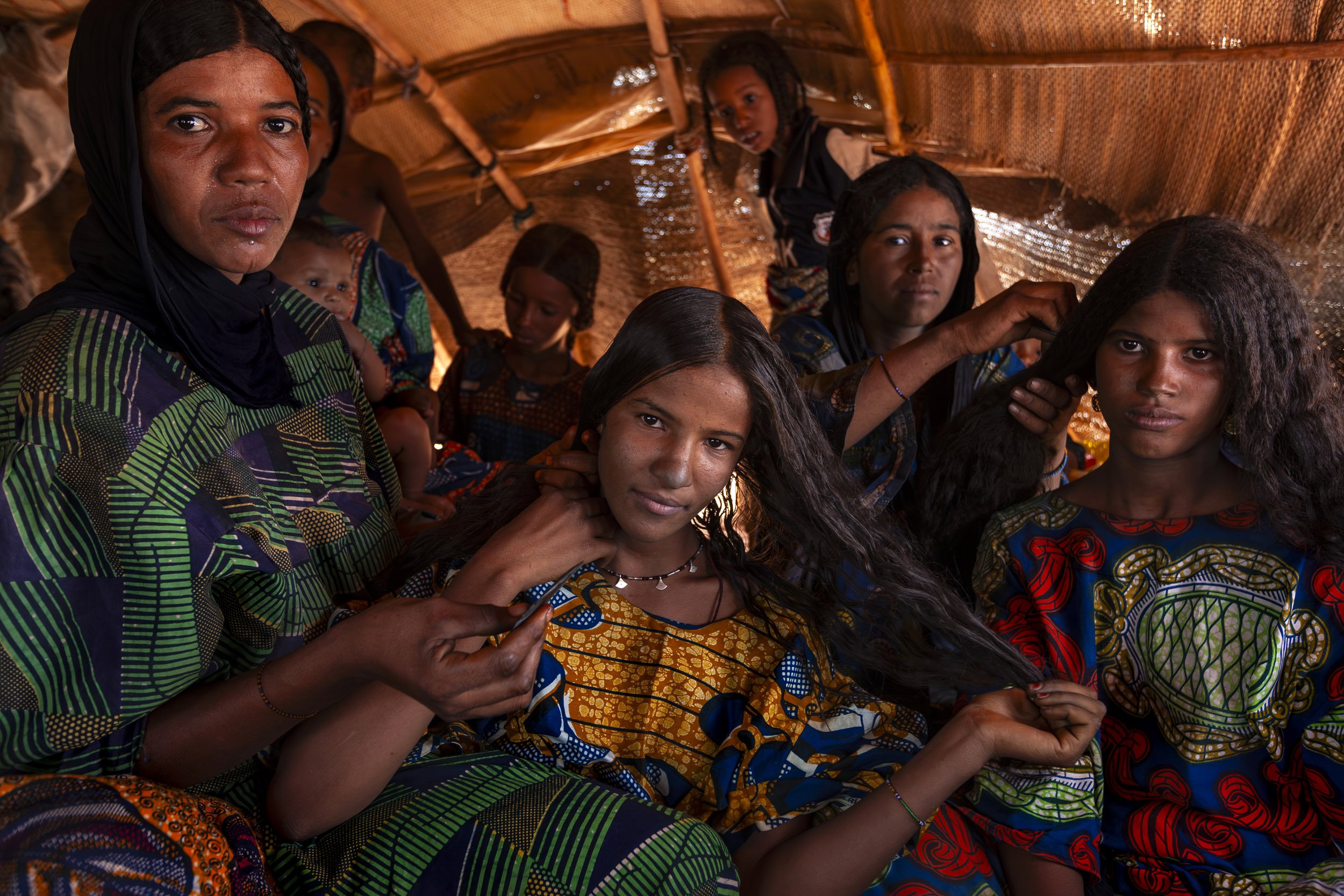 INGAL, NIGER, OCTOBER 2009: Two young Tuareg women have their hair dressed by other Tuareg women inside a traditional nomad tent at a Tuareg Nomad camp, Ingal Region, Niger, 11 October 2009. Tuareg Nomads have two traditional priorities, their anima