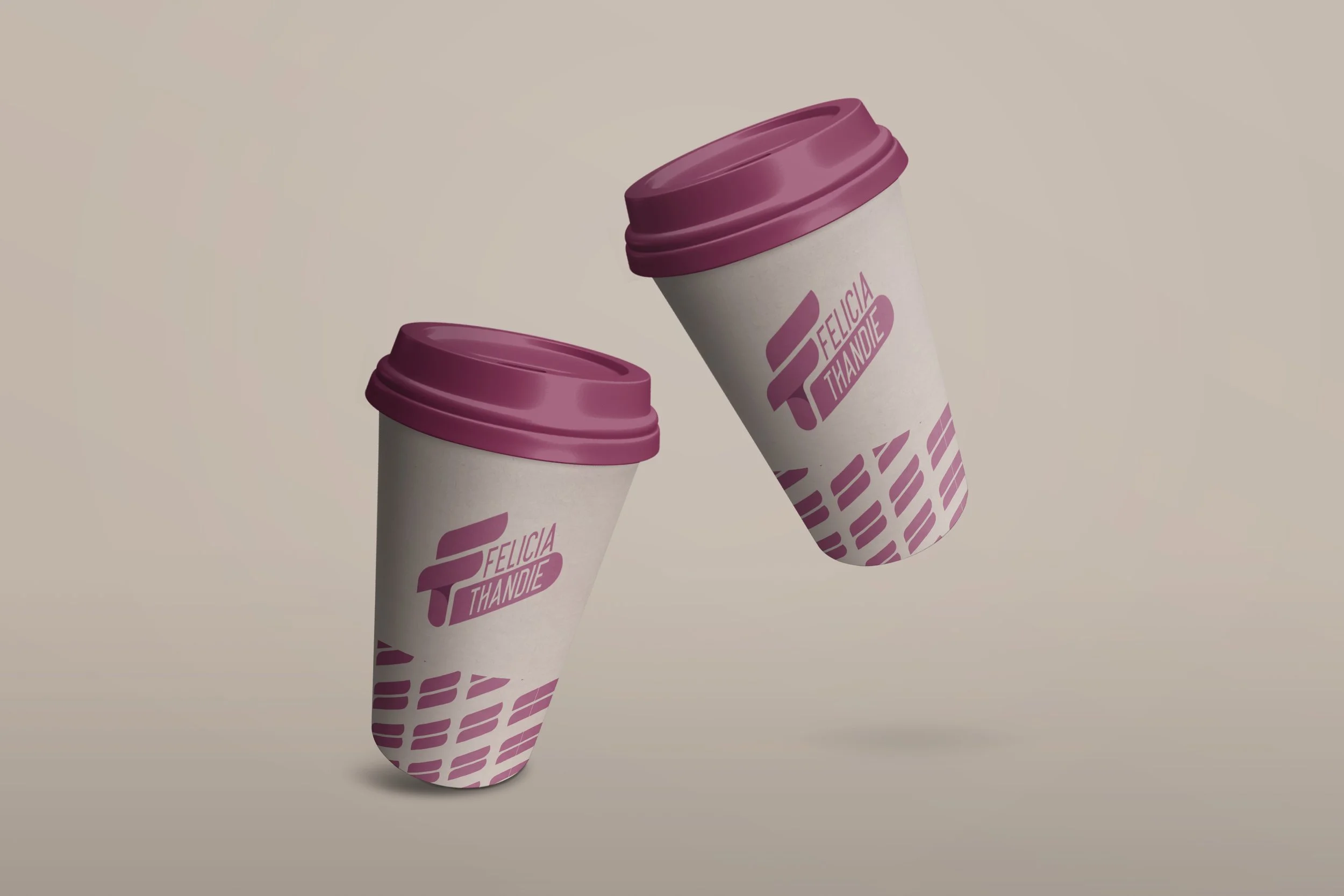 Two disposable coffee cups with purple lids and a logo reading Felicia Thandie, floating against a plain background.