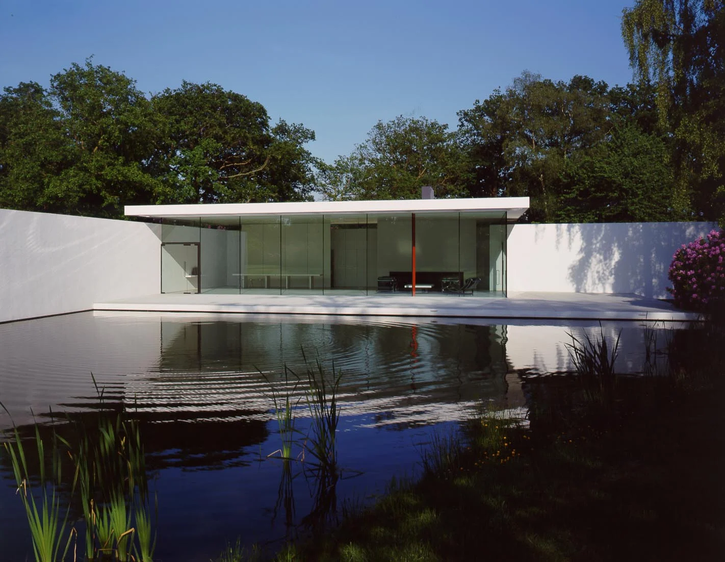 The main living space - a double square in plan with a high frame-less glass wall - faces west over the lake.The rectangular form of the glass box is continued by the clerestory windows that run along the tops of the walls that extend towards the lake and the landscape.