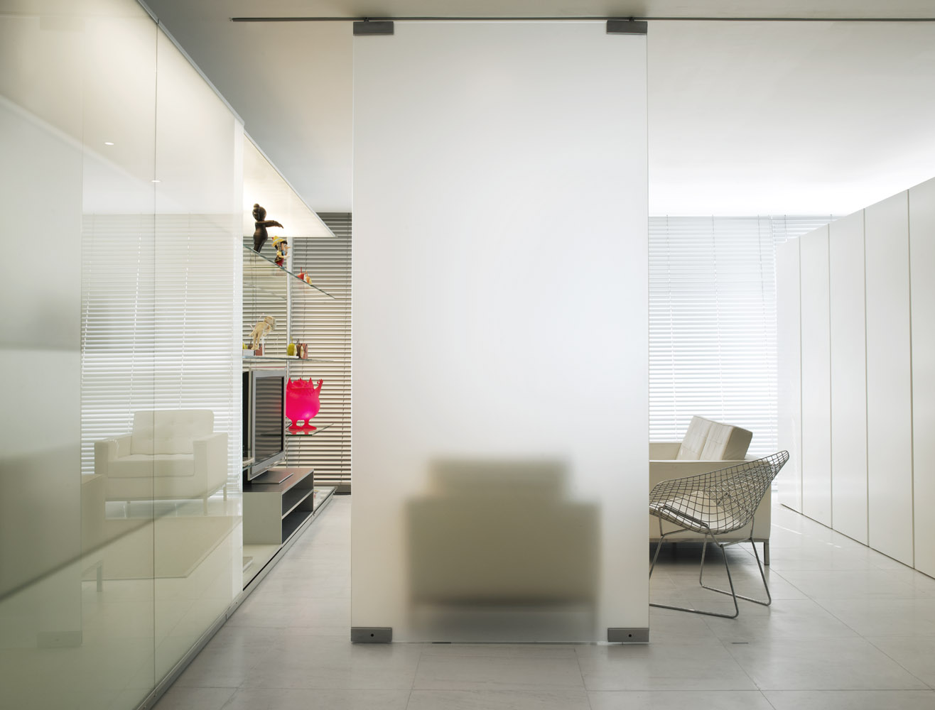 View from entrance of revised interior with TV in glass display system and freestanding island of storage.