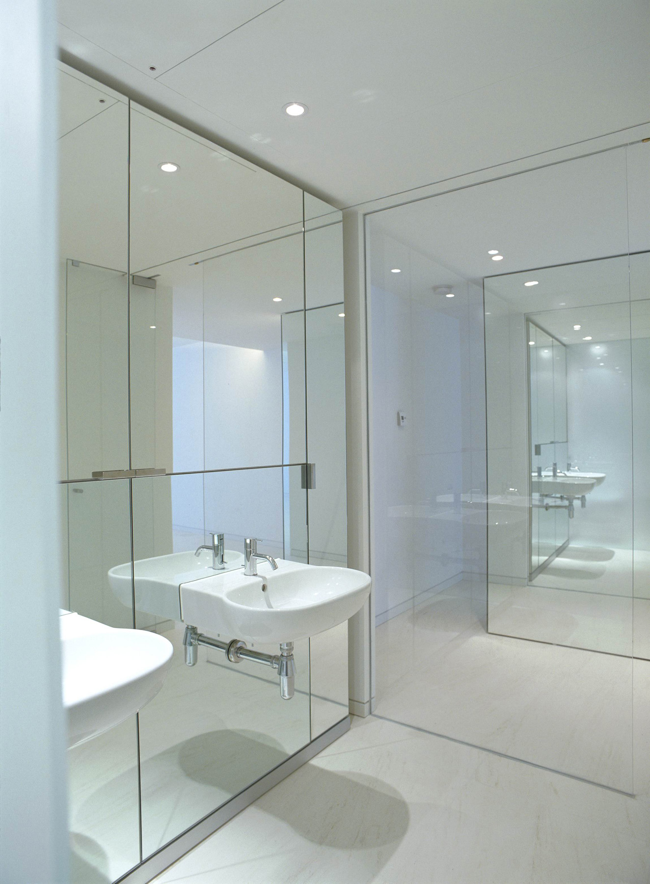 Mirrored bathroom with glass wall to hallway. 
