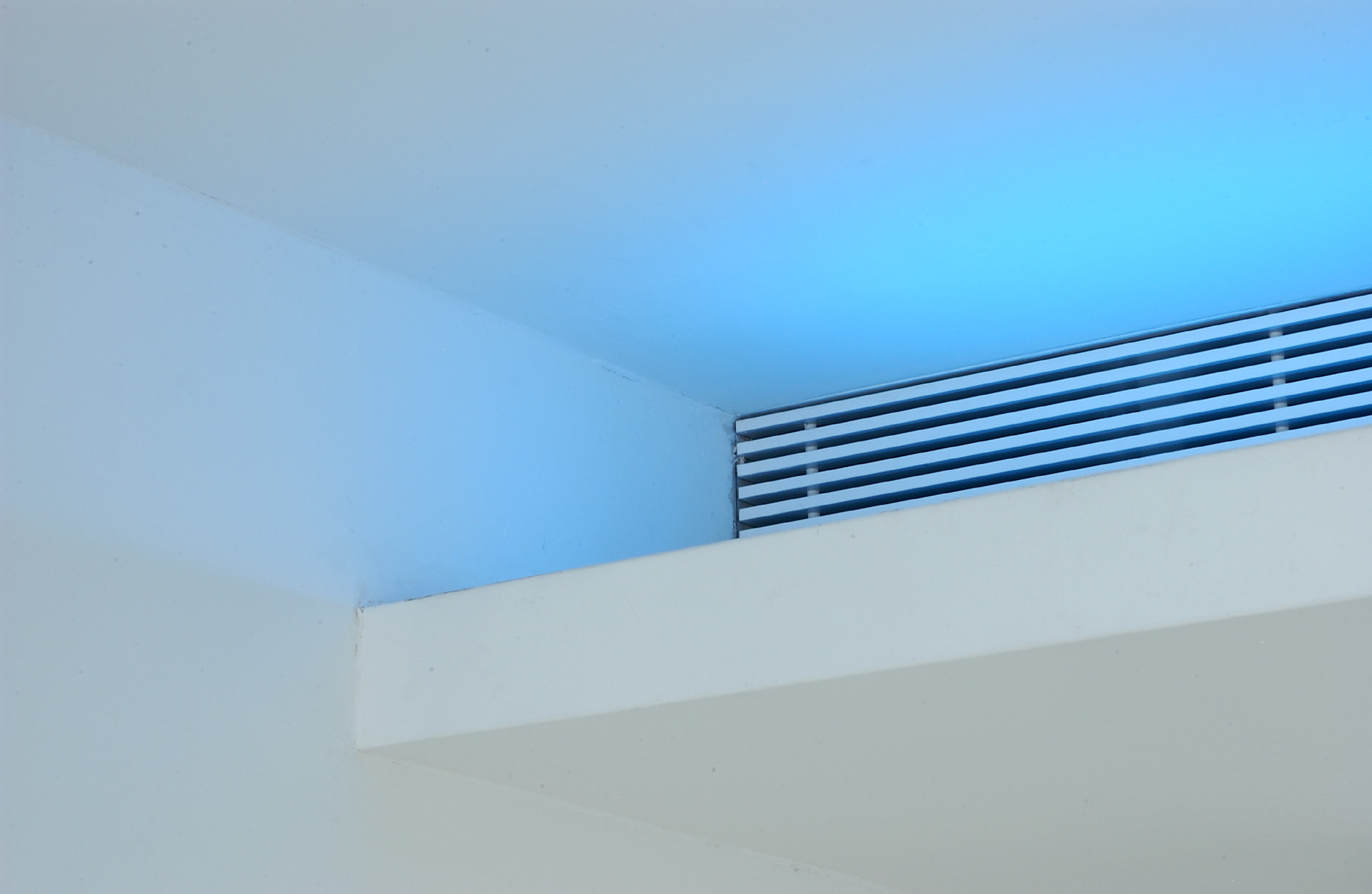 The cantilevered lighting shelf over the kitchen hides a continous air conditioning grille and is fittee with a system of blue and white indirect lighting.