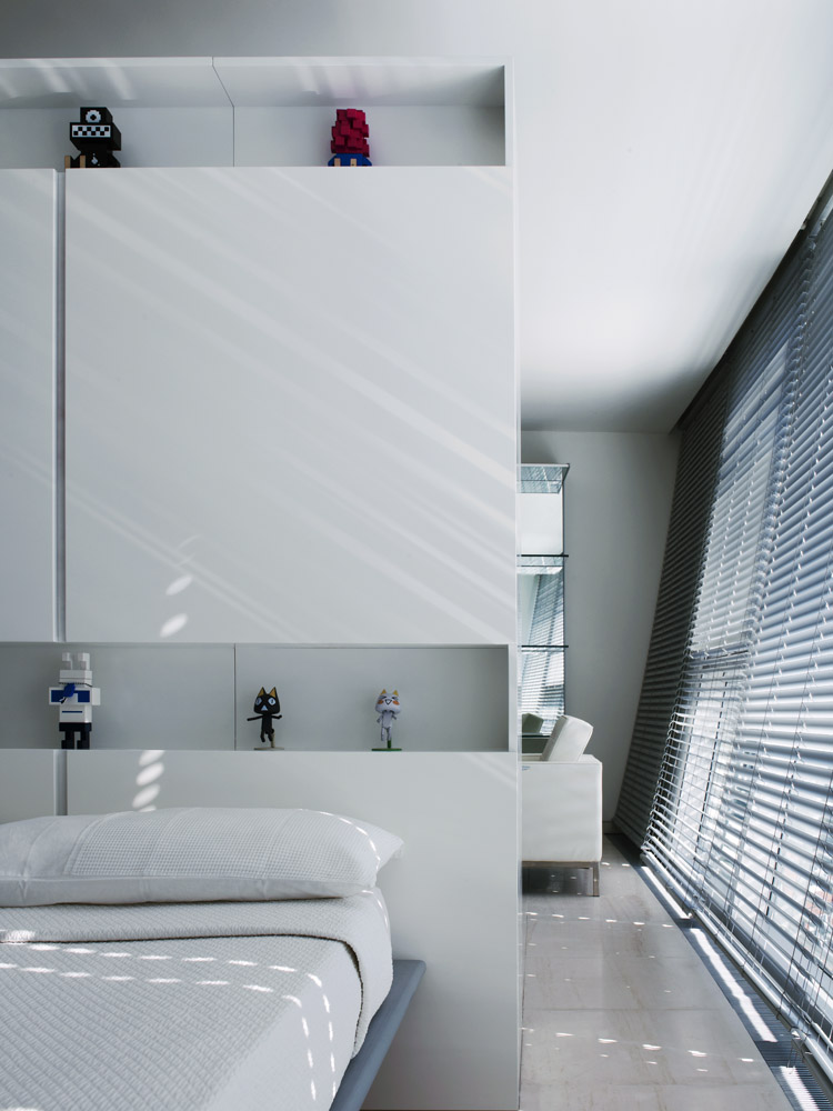 The central storage unit acting as headboard to the bed showing the motorized aluminium louvers to the window wall.