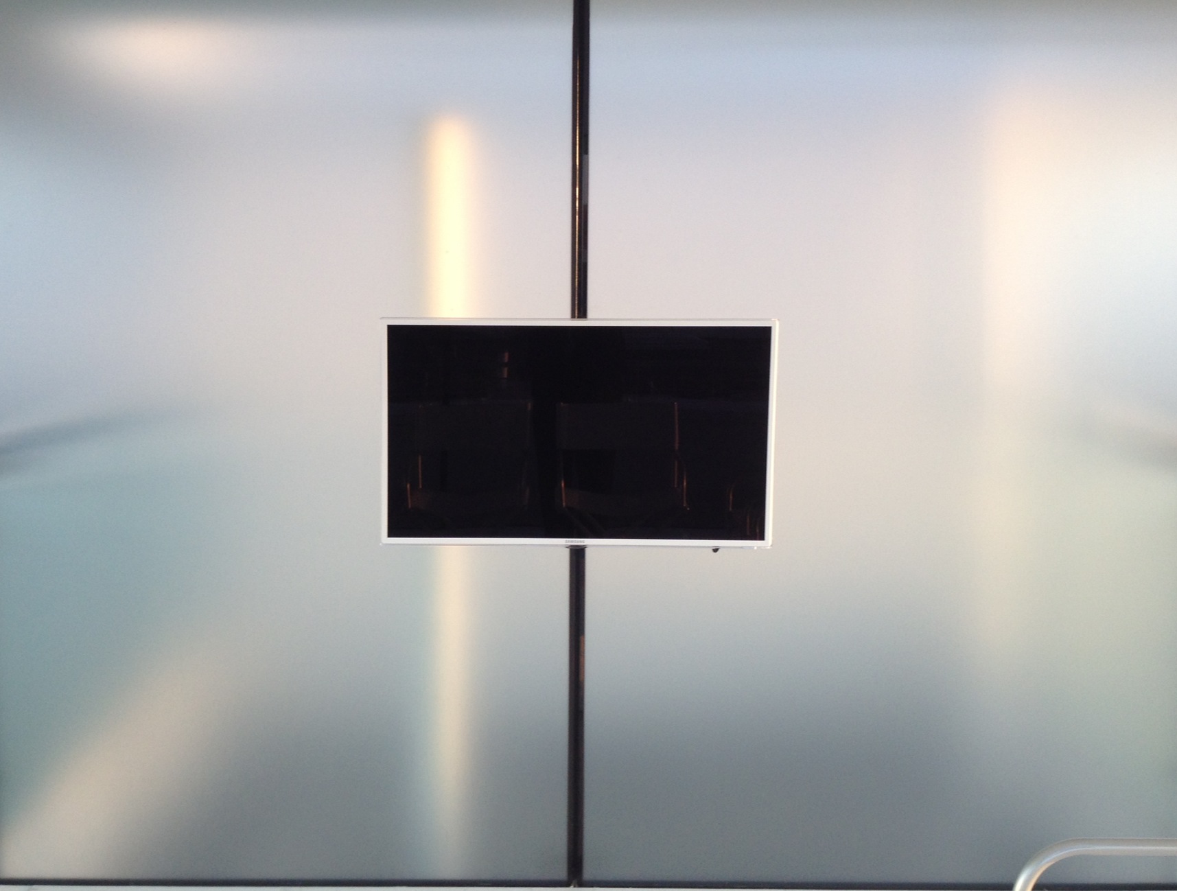 Flat screen TV mounted directly onto an ec=external glass wall of the sun room with cables concealed in the silicone joint between the glass panels.