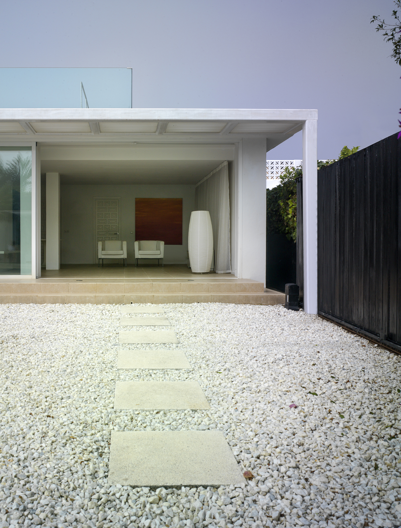 The inset paving slabs define a route through the white gravel from the swimming pool to the louvred canopy and full width steps of the main living space.