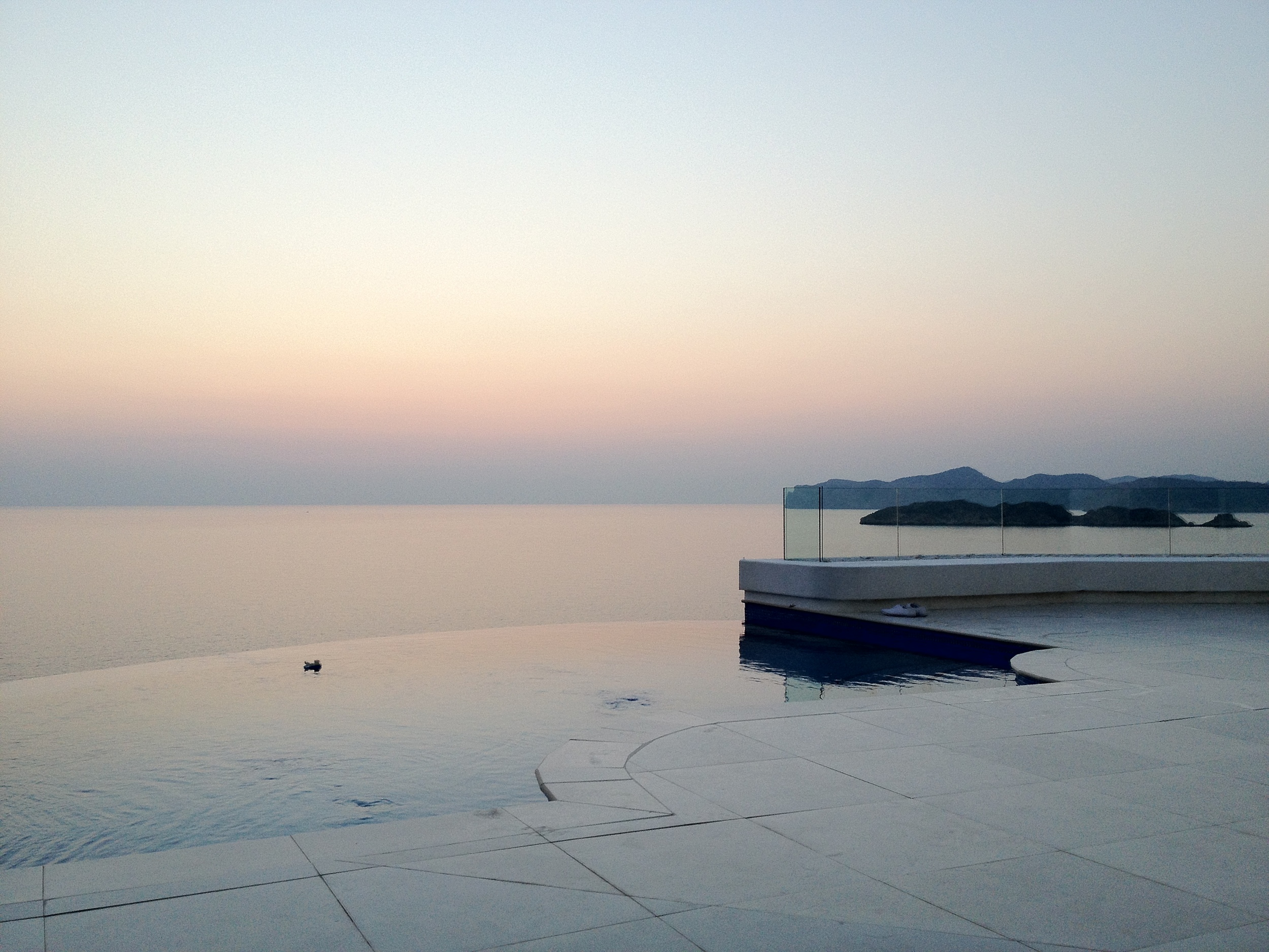 The renovated terrace with its infinity pool and glass balustrade at dusk.