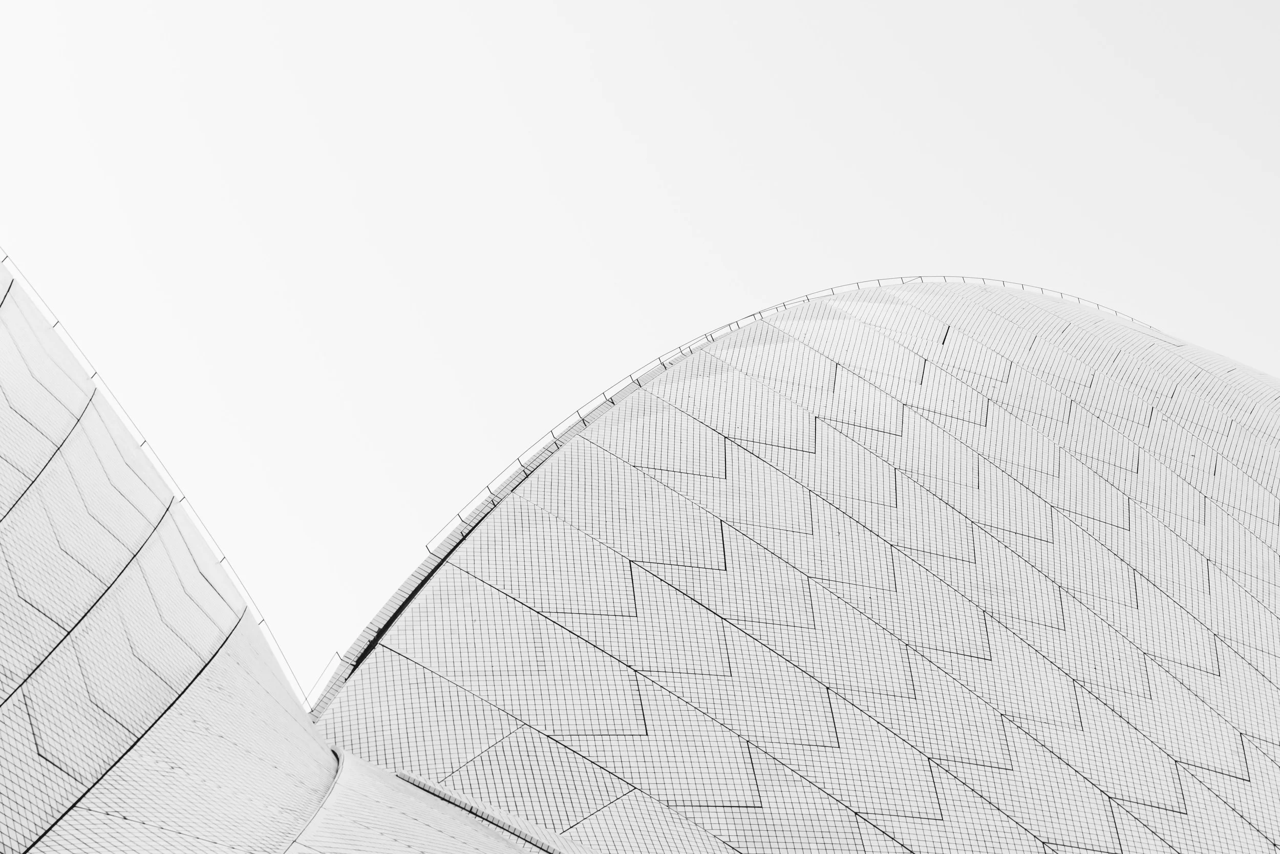 Close-up view of the Sydney Opera House roof with its distinctive white sail-like structures against an overcast sky.