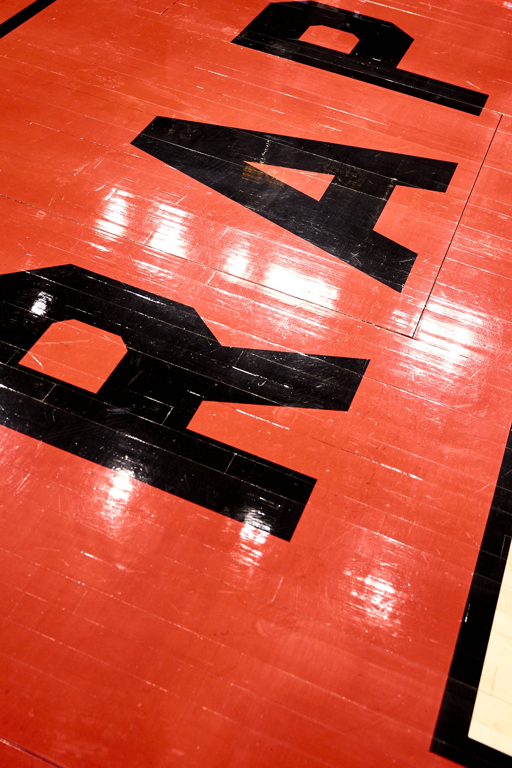 A red and black gymnasium or sports court surface with large black painted areas and lines.