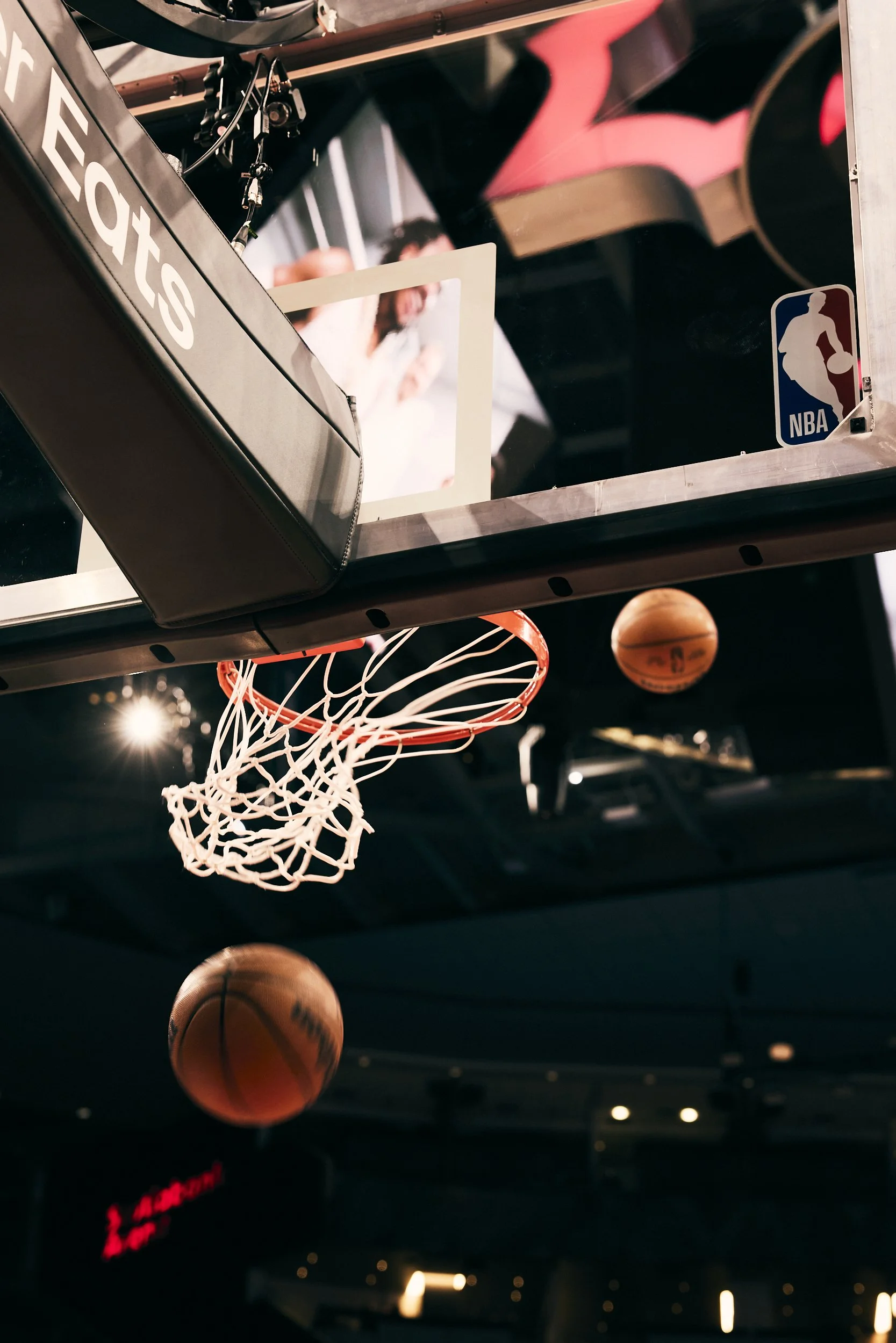 Basketball going into the hoop at an indoor NBA basketball court.