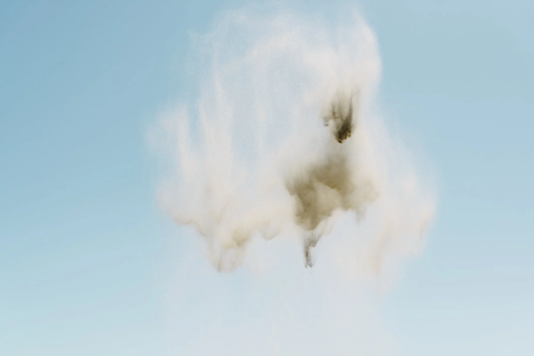 Sand thrown into the air against a clear blue sky.