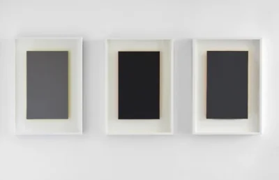Three of Susan York’s Achromatopsia series, which are shades of grey with green, orange, and yellow illuminating from behind.
