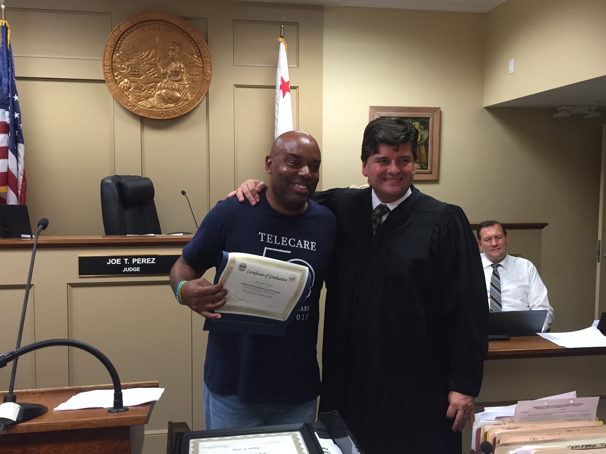 Thurman Williams (left) is handed a graduation certificate for completing the Assisted Intervention program from Judge Joe T. Perez (right).