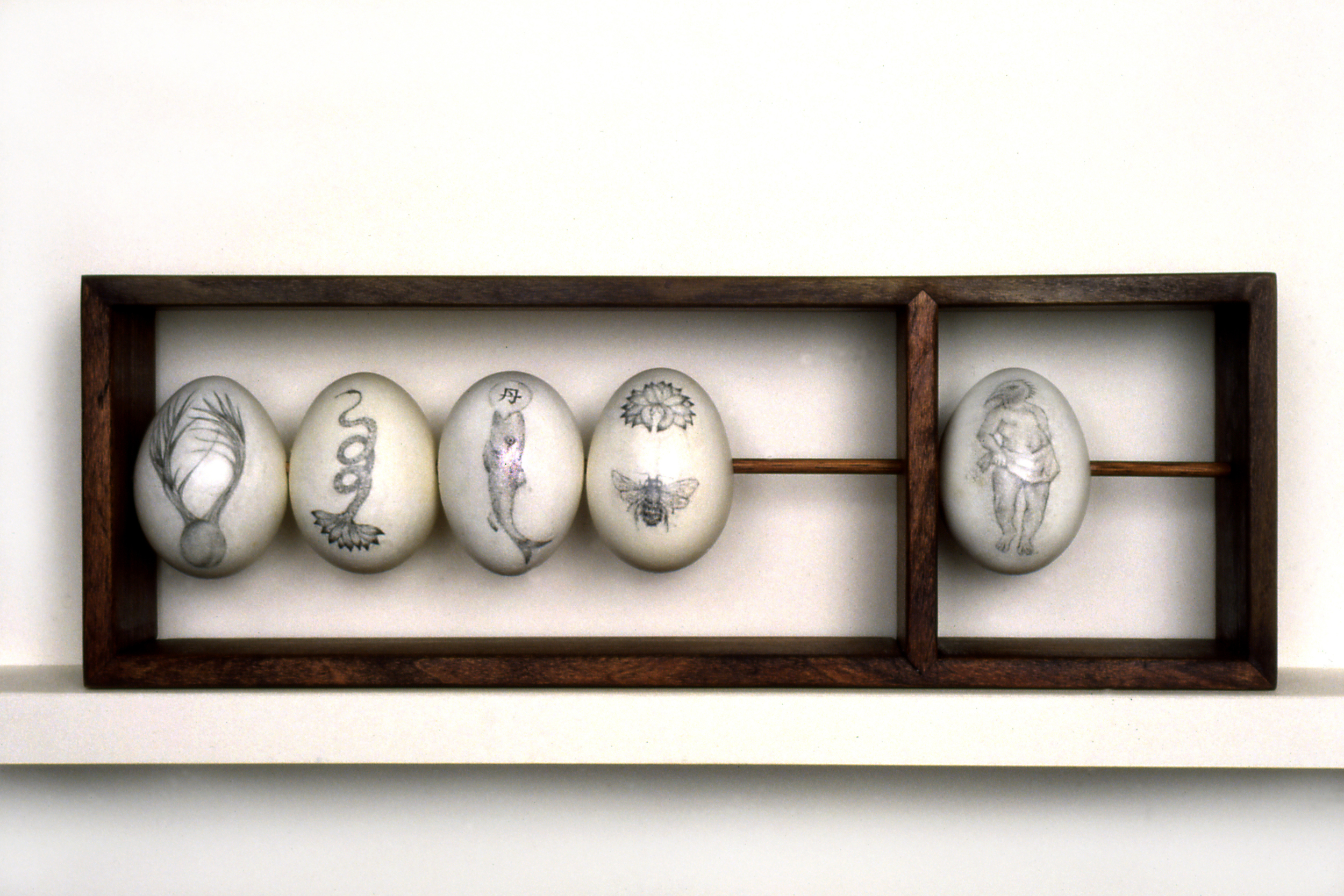 ABACUS The egg "beads" on this one-row abacus are embellished with graphite drawings of hybrid transformational symbols from various cultures, suggesting an alternative approach to mathematical certainty.