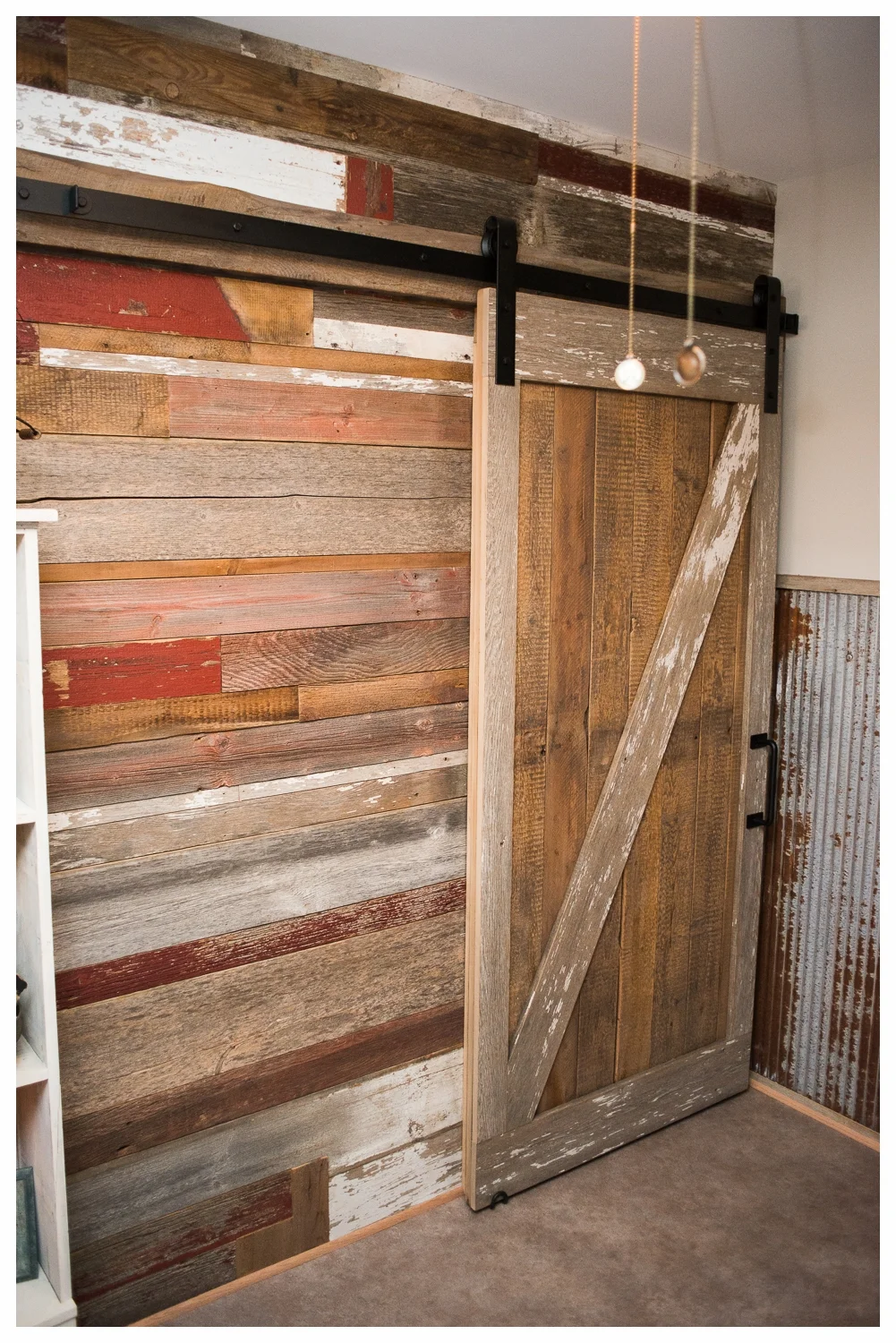 A sliding custom barn door rests against a rich patchwork of different barn wood planks.