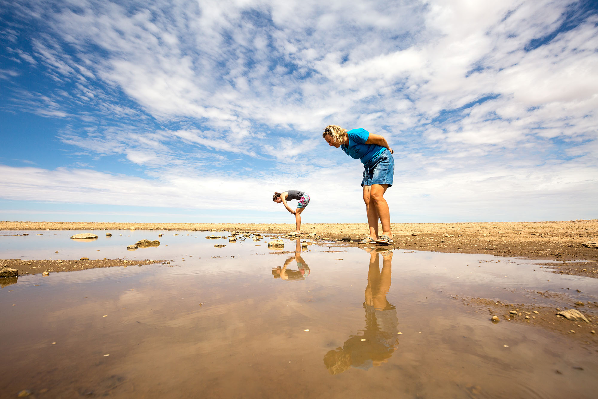 Angela Curtis (right) and Monja Gerber, researchers at Gobabeb, examine a lone temporary pool containing Triops on the central Namib gravel plains.