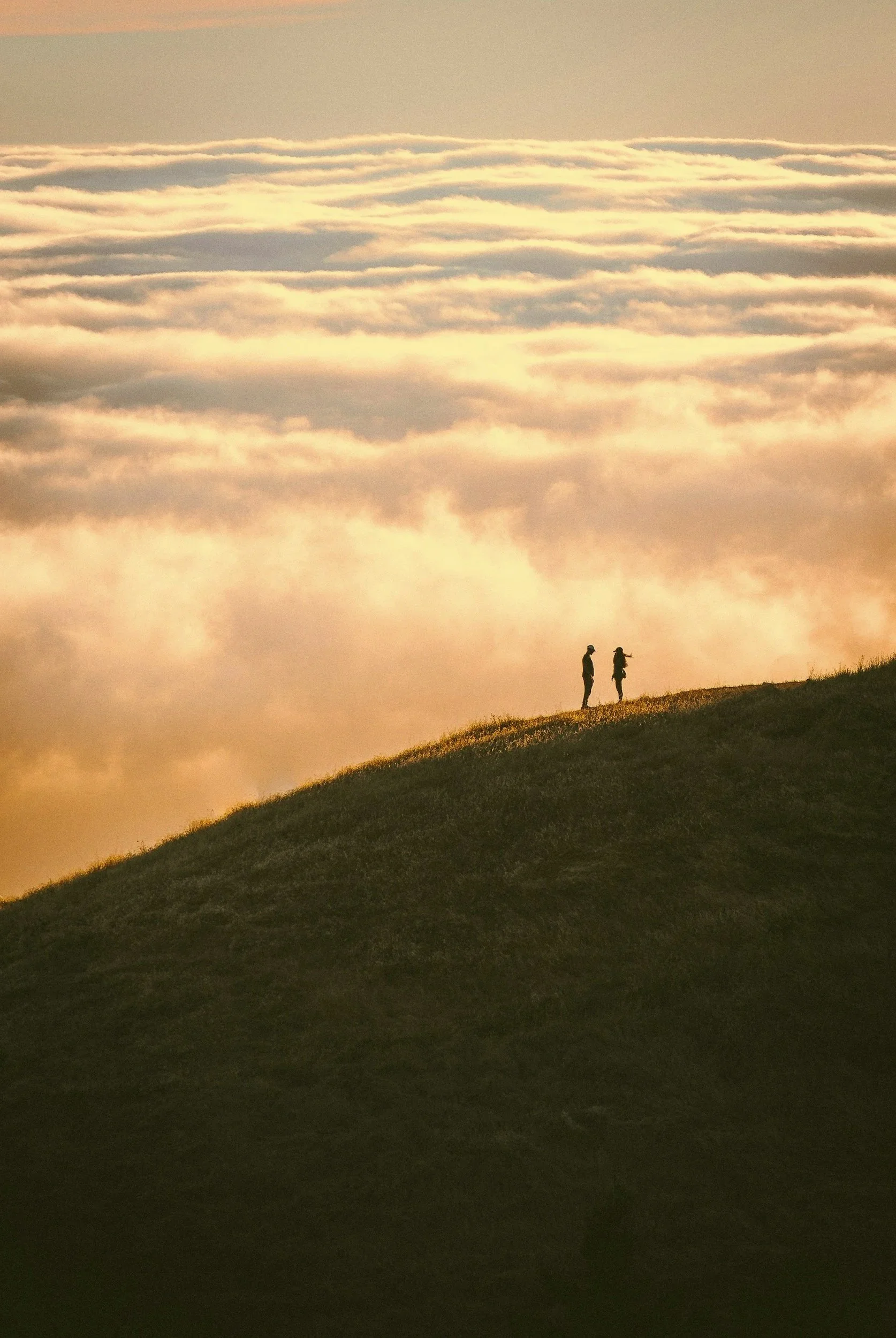 Couple walking together along a mountain ridge above the clouds