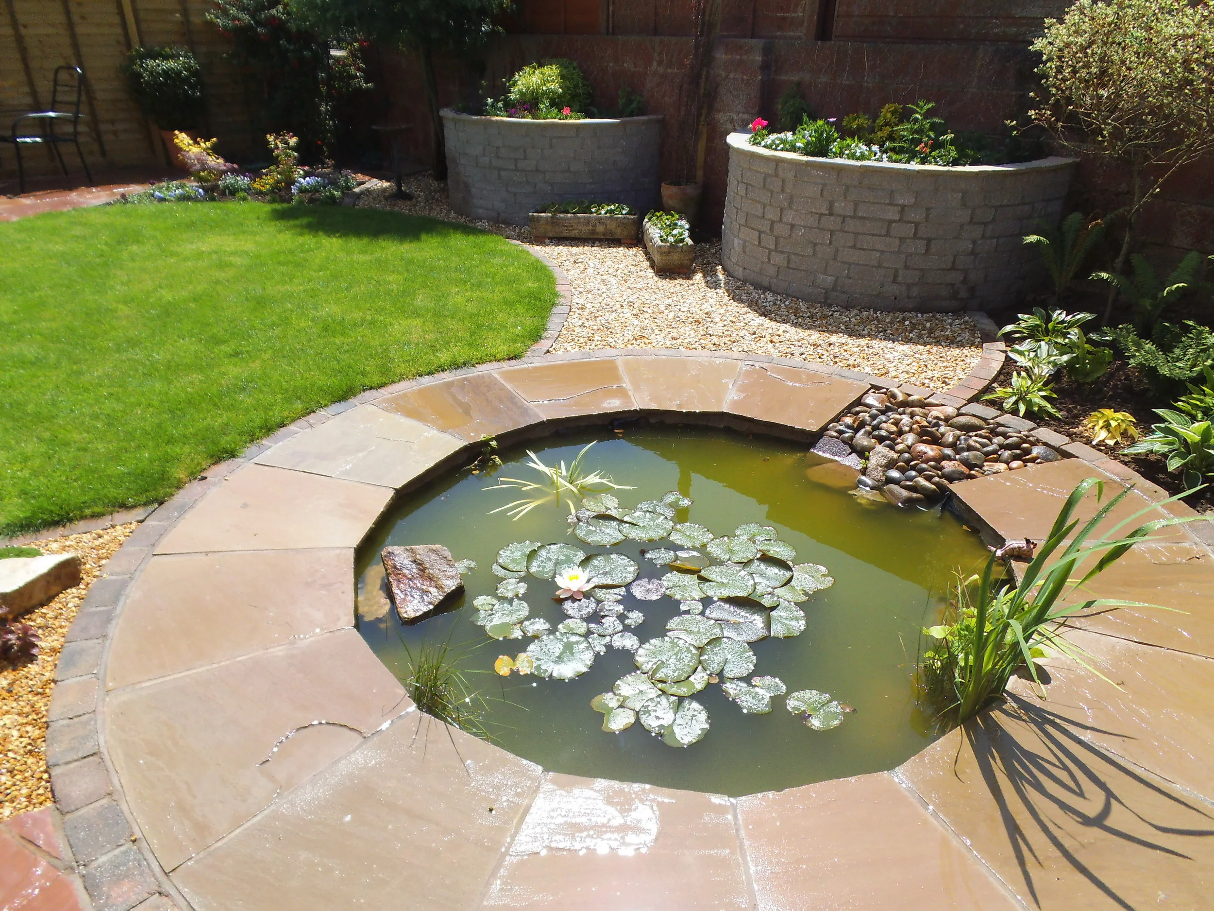 circular pond with sandstone paving.JPG