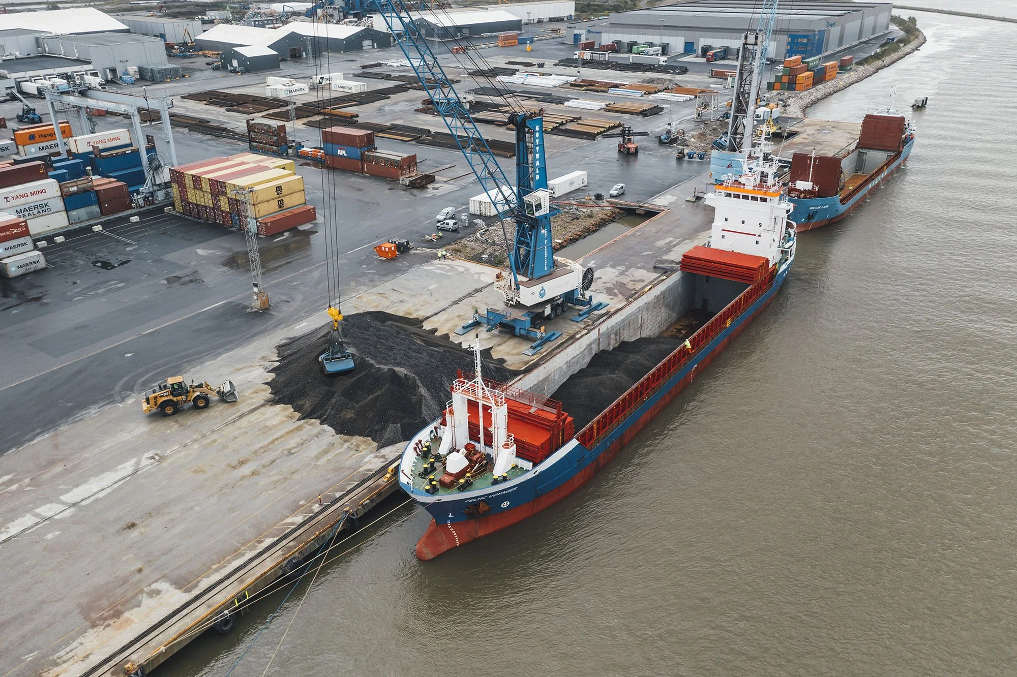 Industrihavn med lasting av glass fra kran til skip, dronefoto