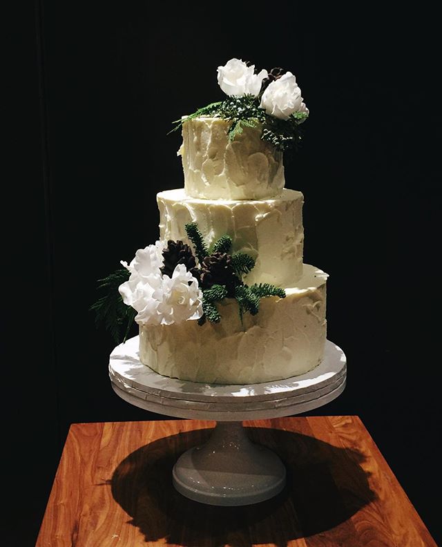 The mix of fresh greenery, sugar roses and chocolate pine cones on this @districtwineryweddings cake is putting me in a solstice mood.