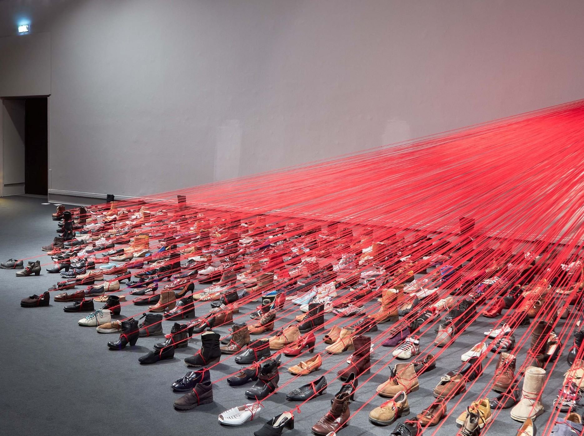 "Over the Continents"di Chiharu Shiota ha legato con km di filo rosso centinaia di scarpe a Palazzo Reale