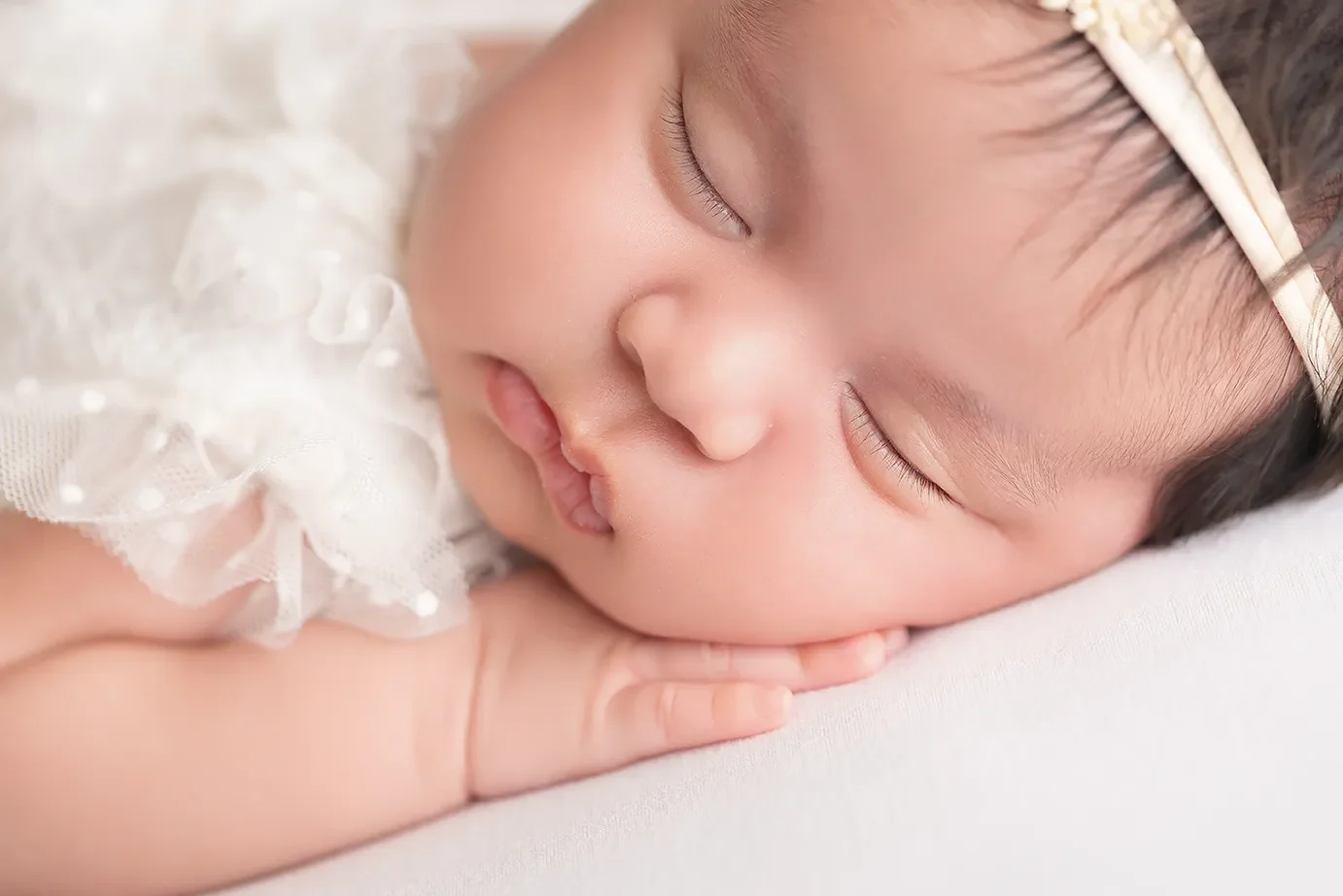  A close up image of a newborn girl in a Glendale studio showing her cheek on her hand.  
