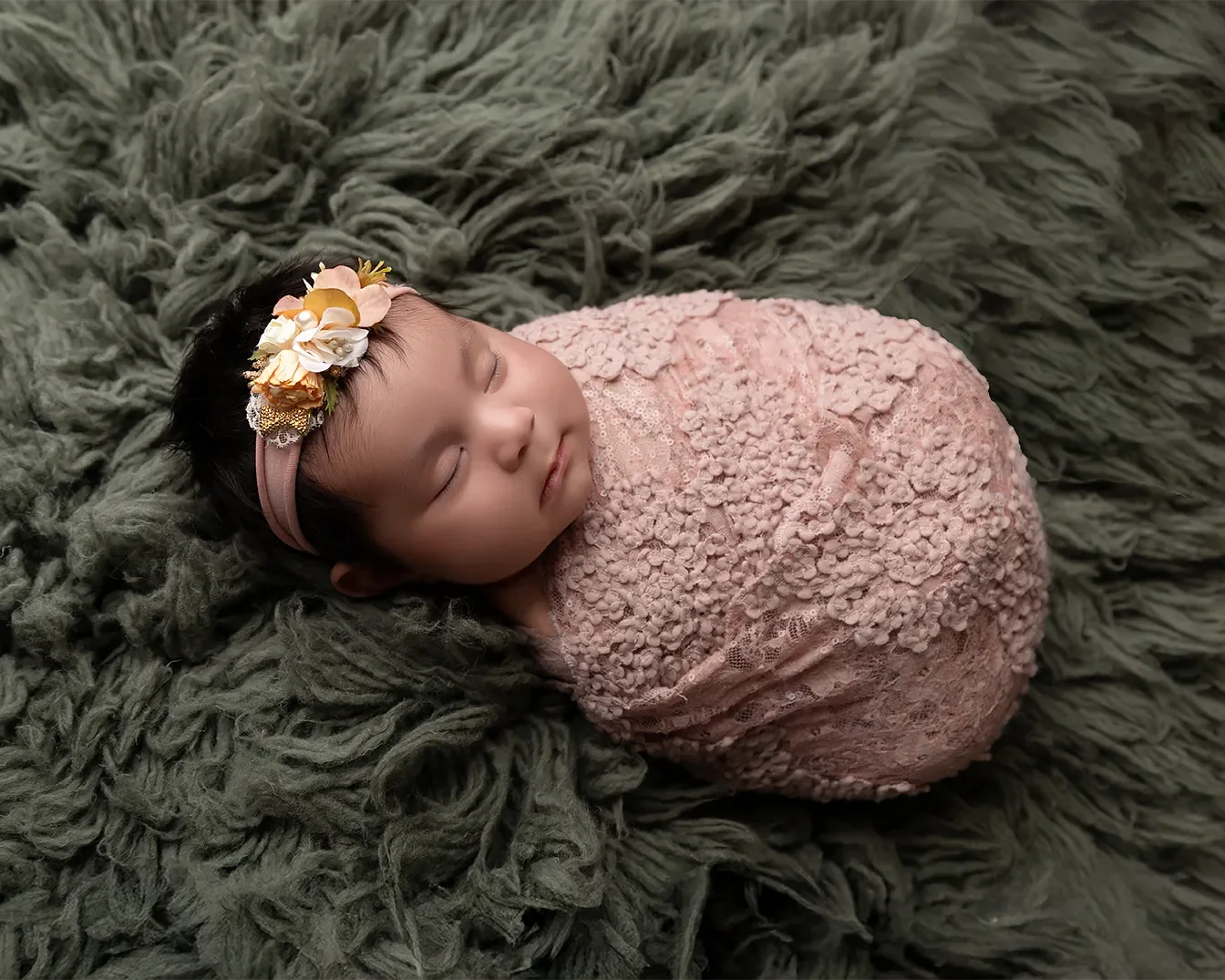  Newborn baby girl photographed in a Glendale California studio wrapped in soft pink lace with matching headband. 