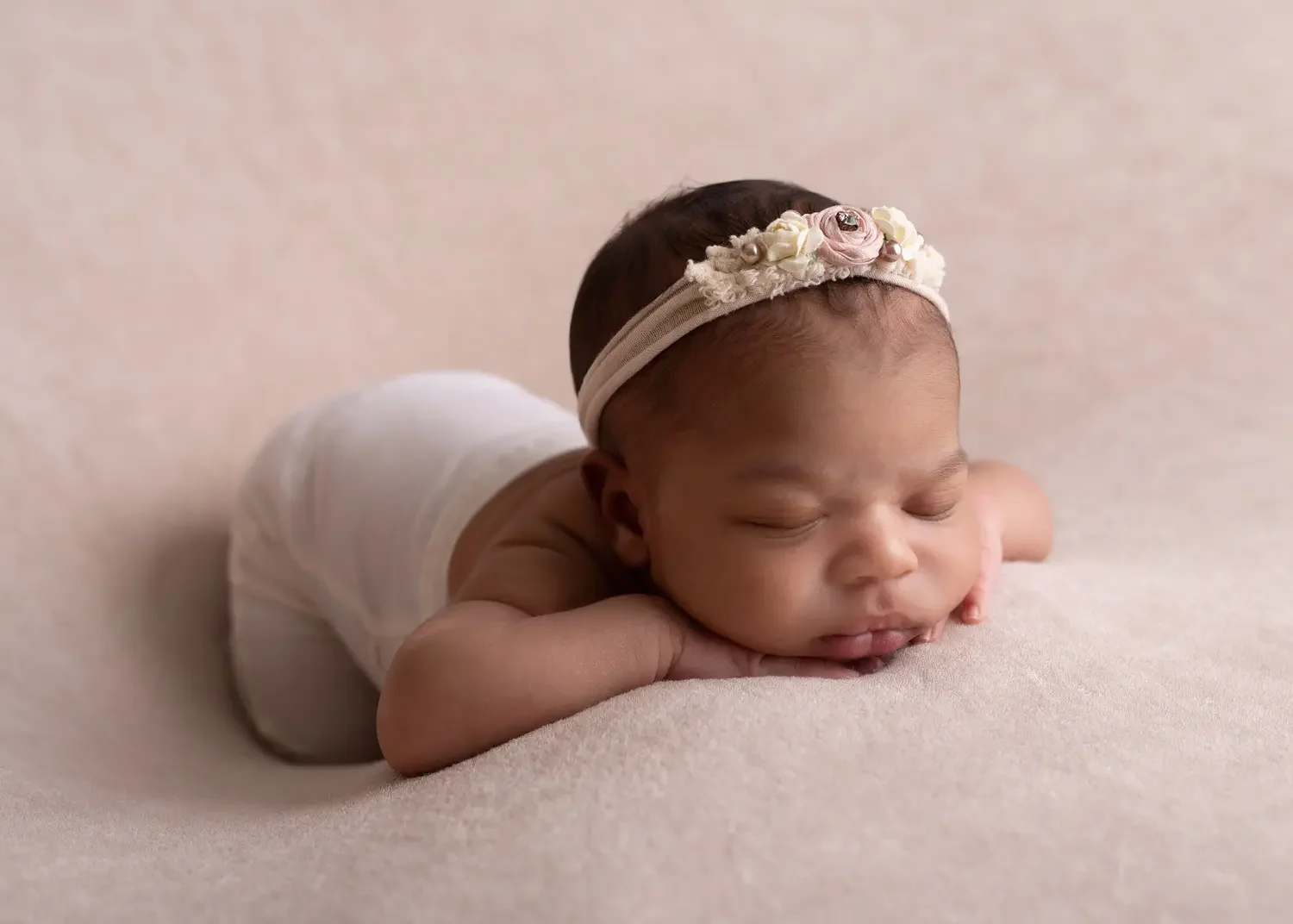  Black newborn girl with chin on hands. 