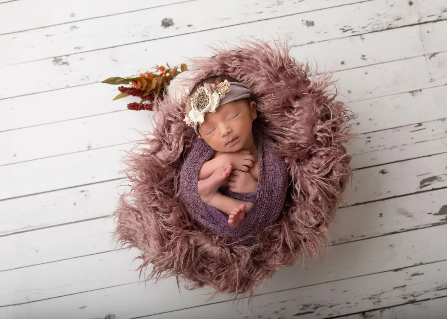  newborn girl in dough bowl curled on back. White wooden floor. 