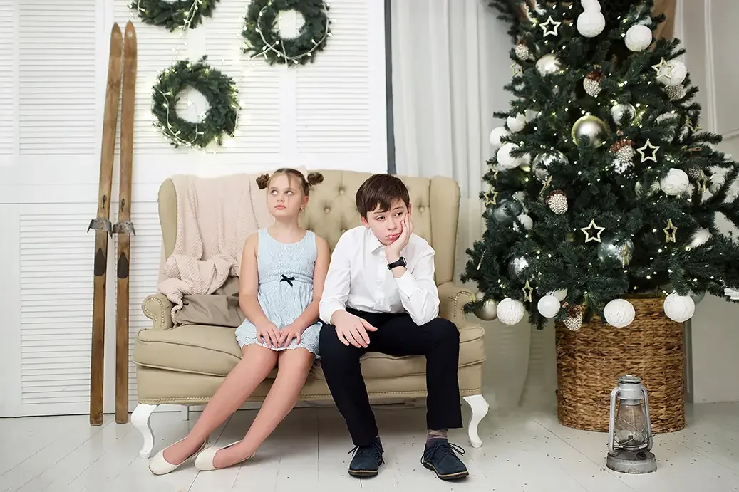 Brother and sister looking bored before a family holiday photo session in a Christmas studio. Helpful example for preparing reluctant children and teenagers for family Christmas pictures by a Glendale and Los Angeles family photographer.