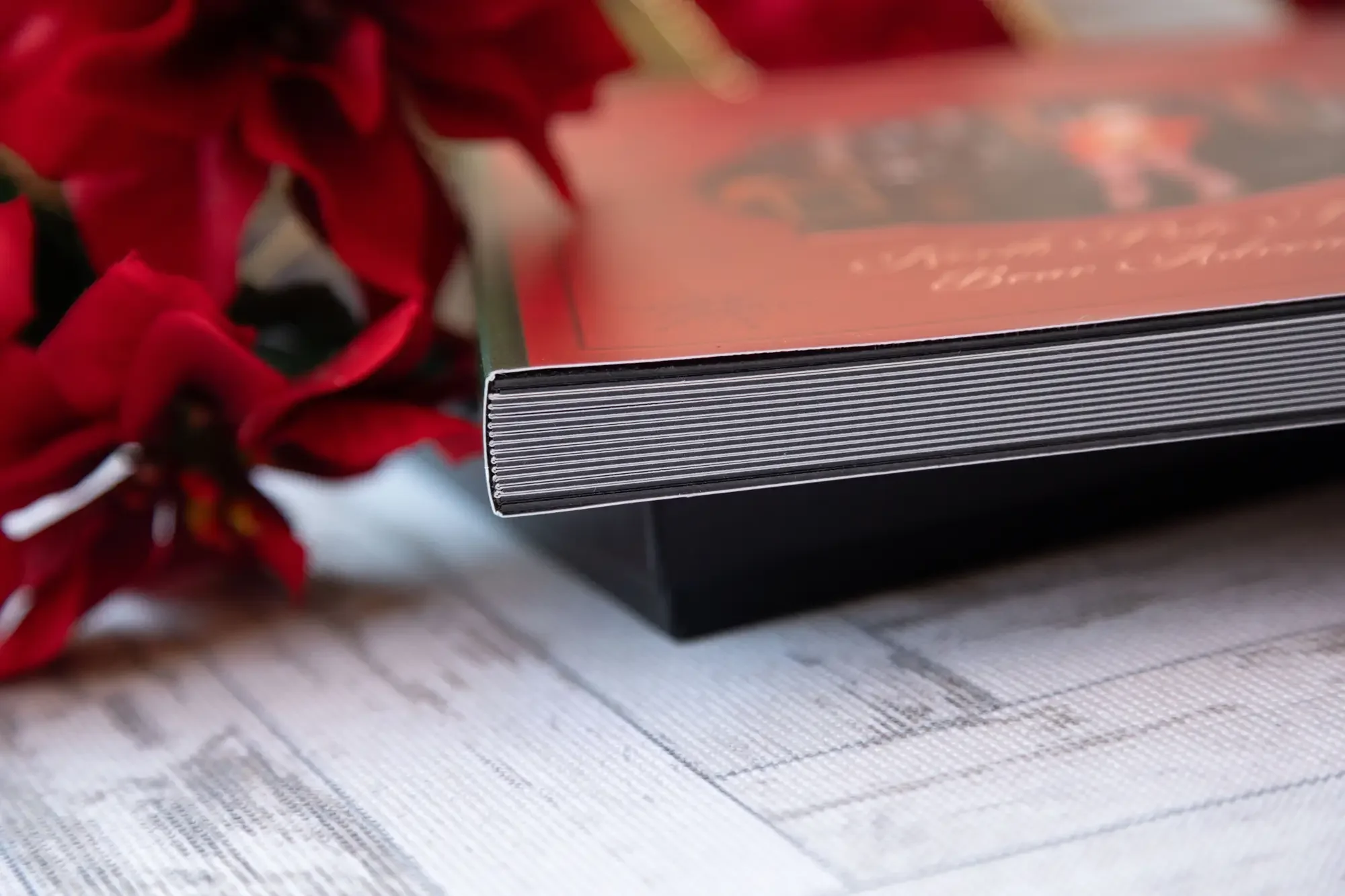 Close-up of a North Pole Teddy Bear Adventure storybook showing the thick lay-flat album pages, displayed on a black keepsake box with red poinsettias.