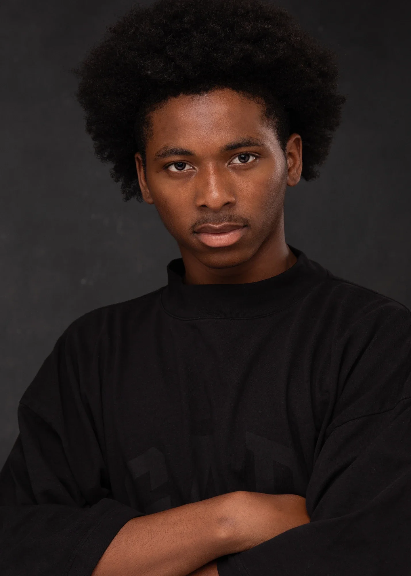 Studio actor and modeling headshot of a young man photographed against a dark neutral background. The close crop, direct expression, and clean styling create a strong contemporary portrait suitable for acting submissions, casting profiles, modeling p