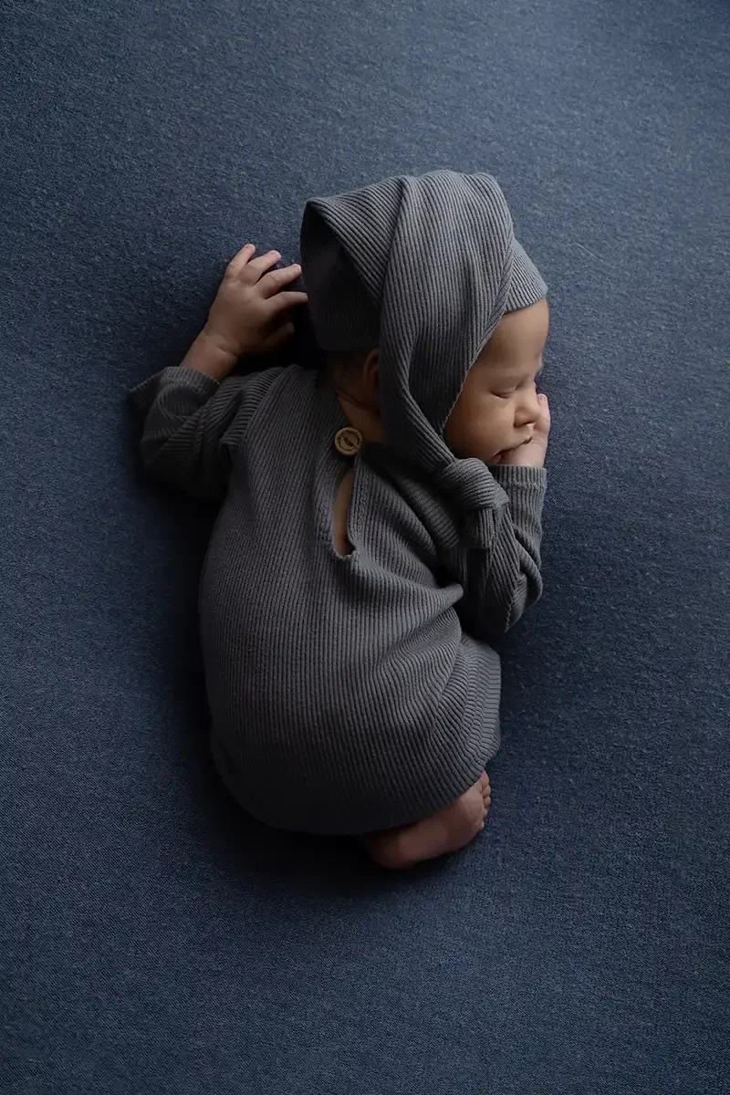Older newborn baby posed in a gray outfit during a studio newborn photography session in Los Angeles.