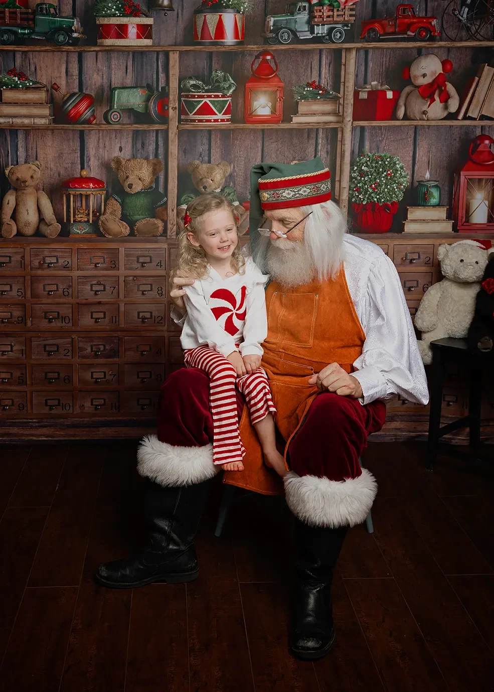 A young girl sitting on Santa Claus's lap, both smiling, in a festive Christmas setting during a private pictures with Santa session near Glendale