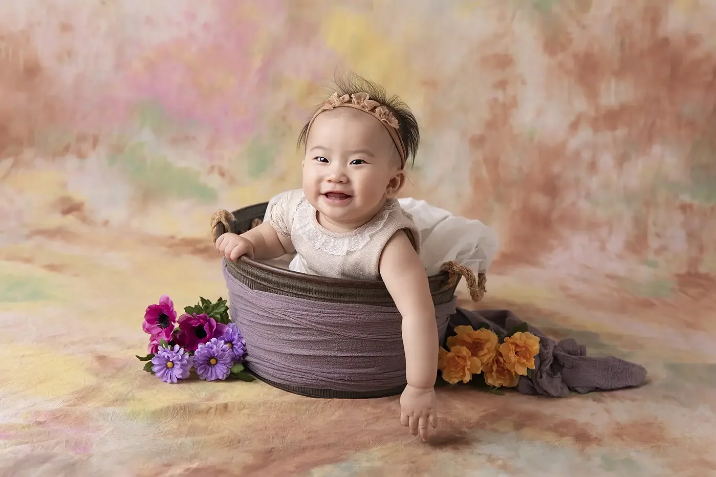 Smiling baby sitting in a floral studio setup during a 6-to-9-month milestone photography session in Los Angeles.