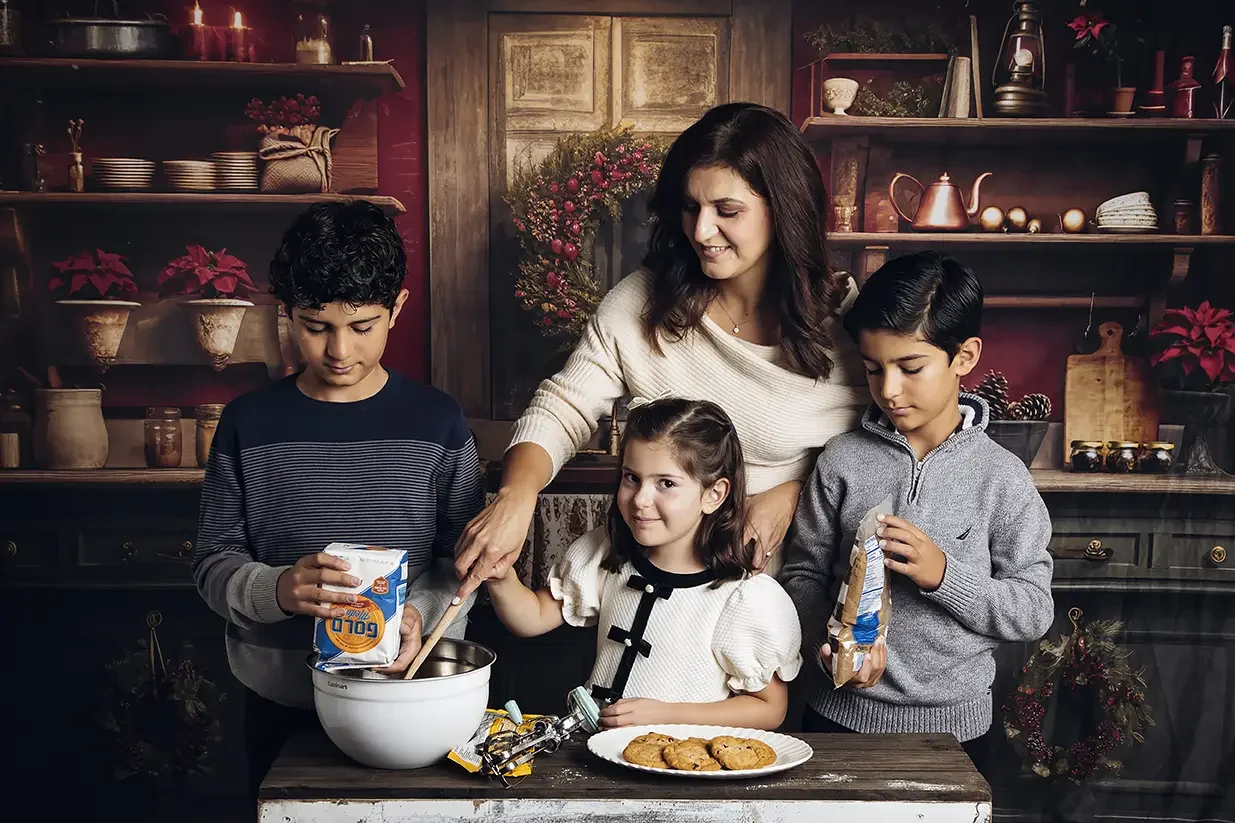 Family decorating Christmas cookies during a holiday family photo session in a Los Angeles studio, capturing natural smiles and genuine family moments.
