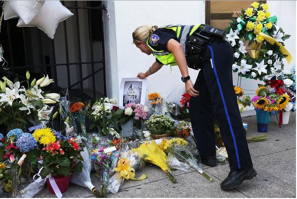 A police officer pays his respects to the murdered victims. Image Source: LA Times