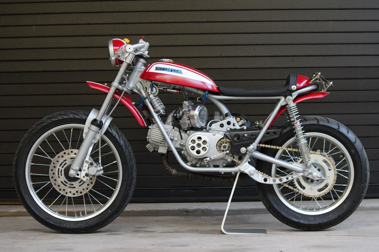   The original tank had pinholes and bad repairs, and was chopped off. CR80 wheels, hubs, rotors and calipers with custom caliper mounts were used. The original footpeg mounts were relocated in a higher rear-set position. 