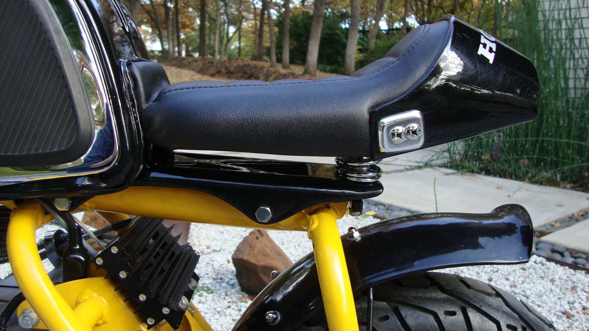  Because there is plenty of room under the tank tunnel, a storage area big enough for a wallet and phone is accessible through a flip-down door at the front of the seat. The seat springs are valve springs from a Ford 289. A billet oil cooler is visib