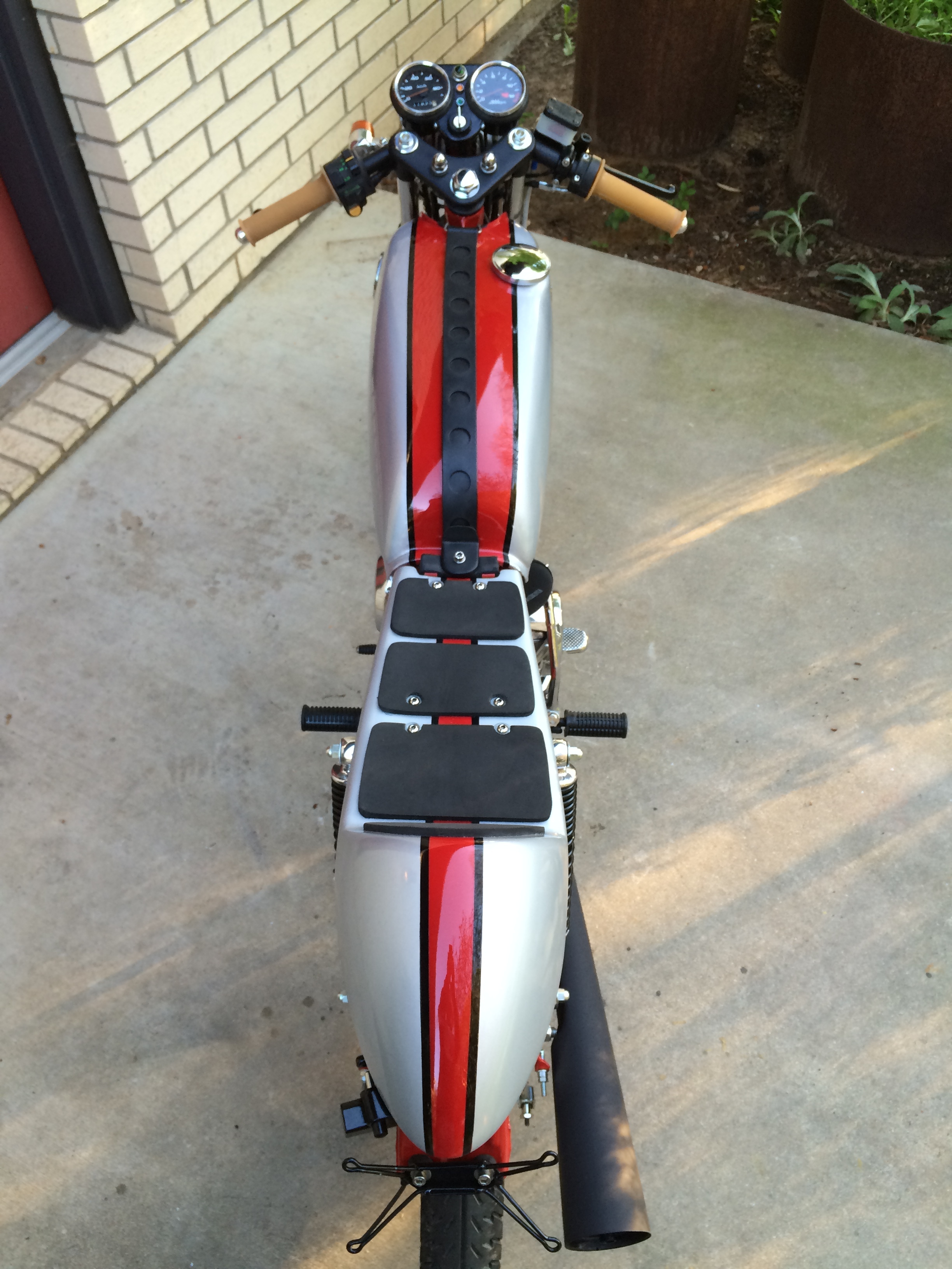The gas filler neck was moved to the side to allow for the placement of a center strap. Stock signals and even the helmet lock were left in place along with a custom license bracket. A custom bracket to house the instruments and head light was also added. The seat was made from a cut-down Tweets brand fiberglass piece, reinforced with extra layers of glass cloth on top of a custom seat pan that also houses the battery.