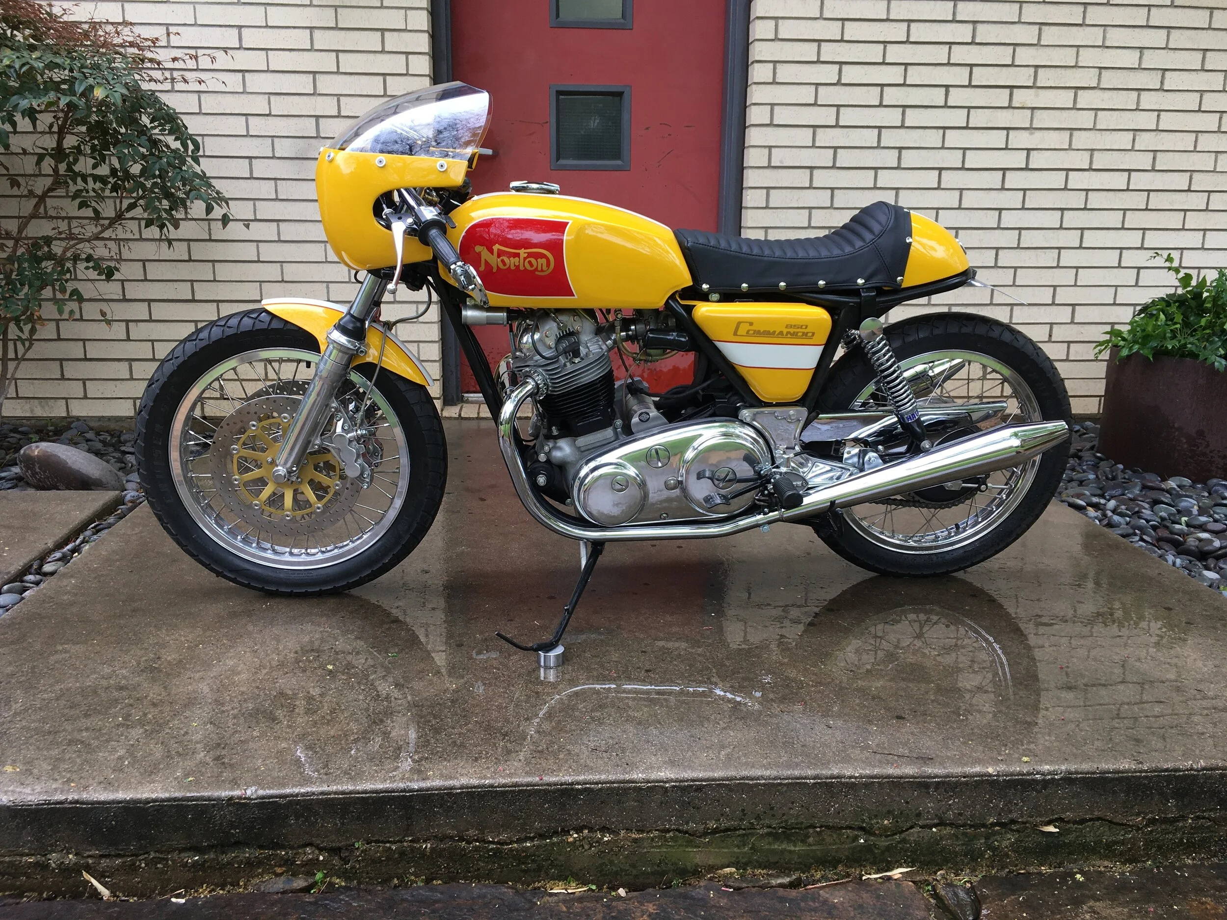  A cafe custom in the spirit of a 1960’s-1970’s British bike was the aim. The original style Norton mufflers replaced a set of short reverse cones that were used in mock-up. The rear-sets and fork brace are Norman Hyde pieces. The bright colors and s