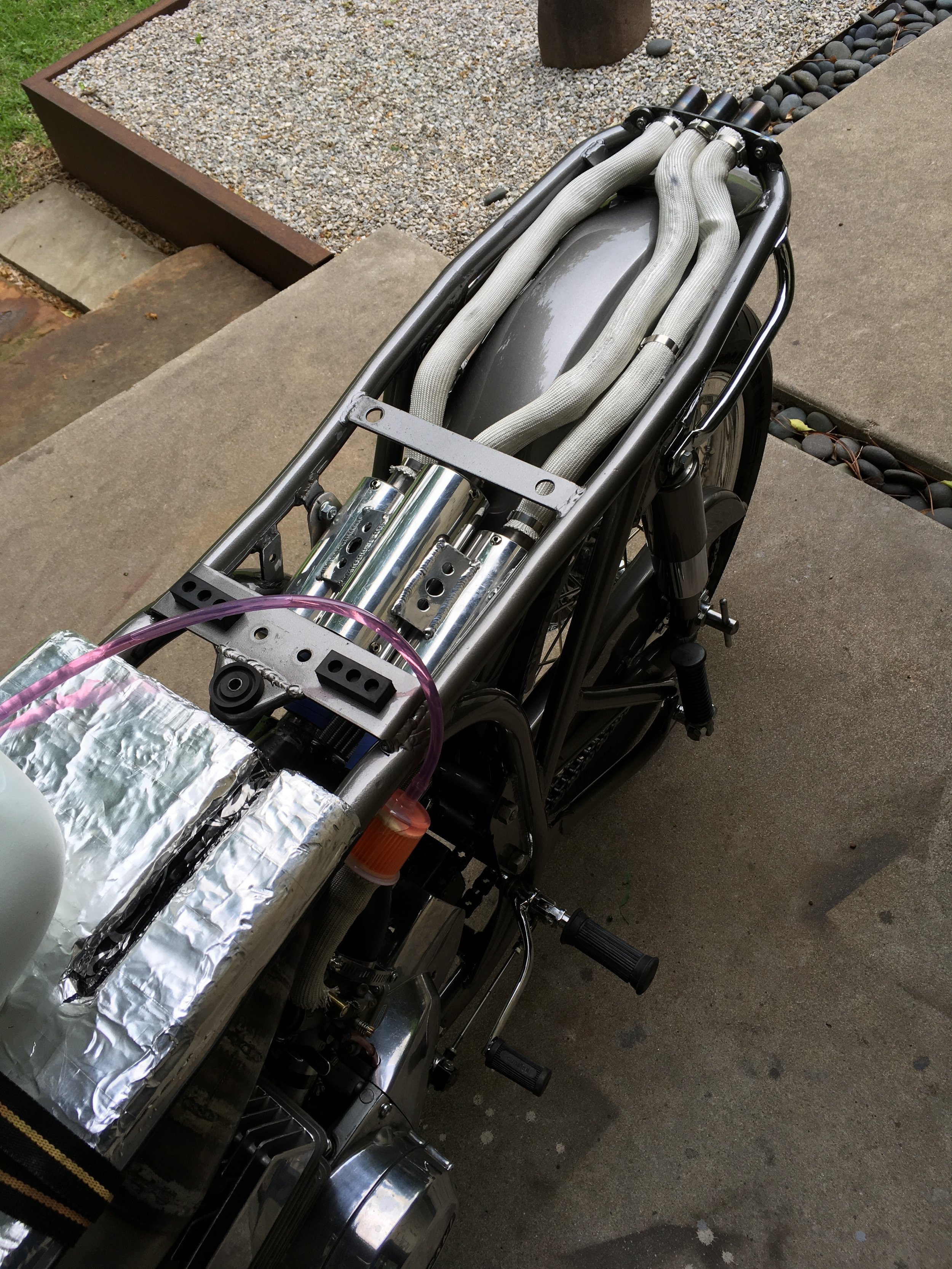  The tail pipe routing and custom frame loop exposed. The original frame ends at the shock mounts, without a loop or crosspiece. Since this was designed for the possibility of two-up riding, the frame loop was essential. 