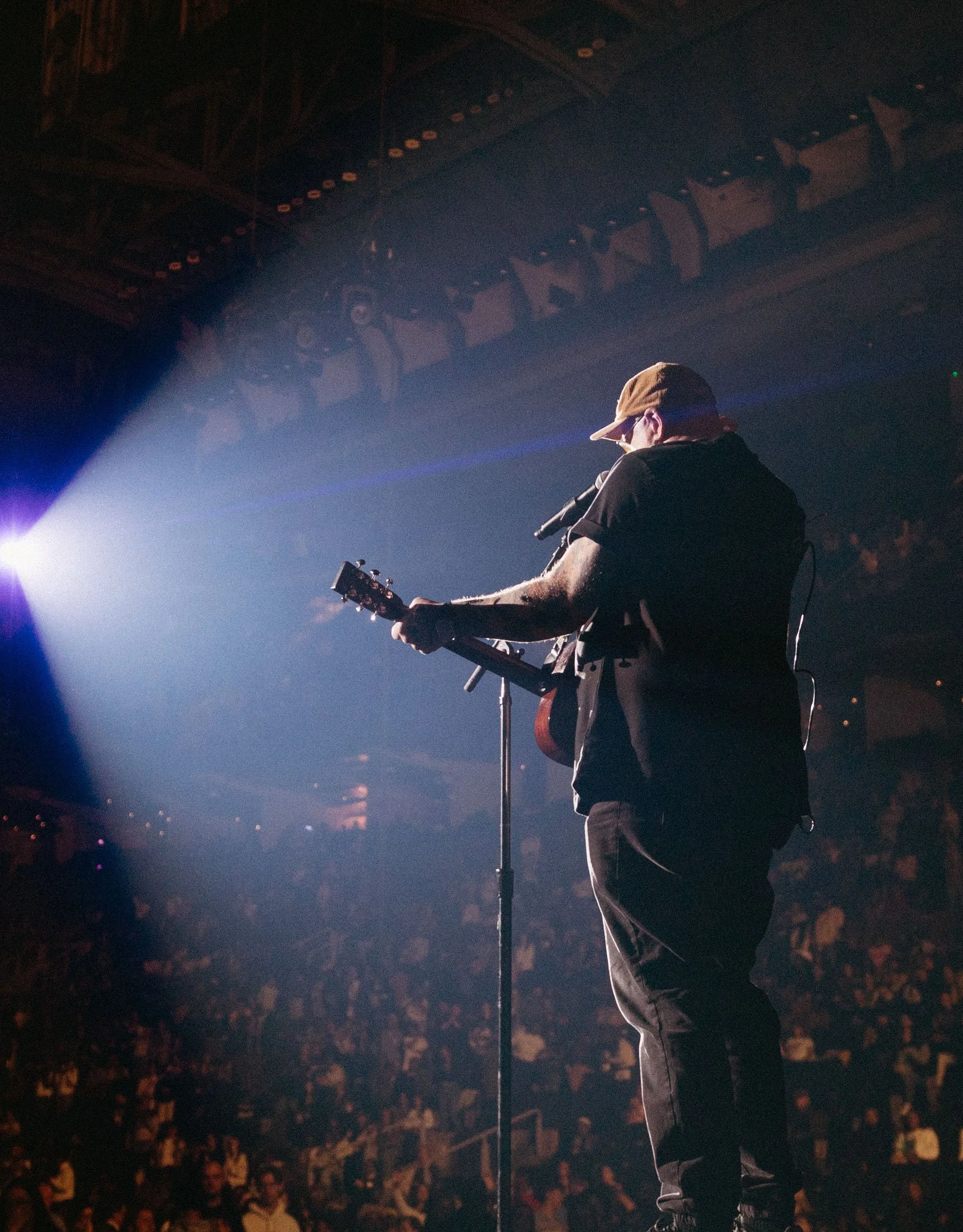 Stephen McWhirter on stage with an acoustic guitar under a spotlight