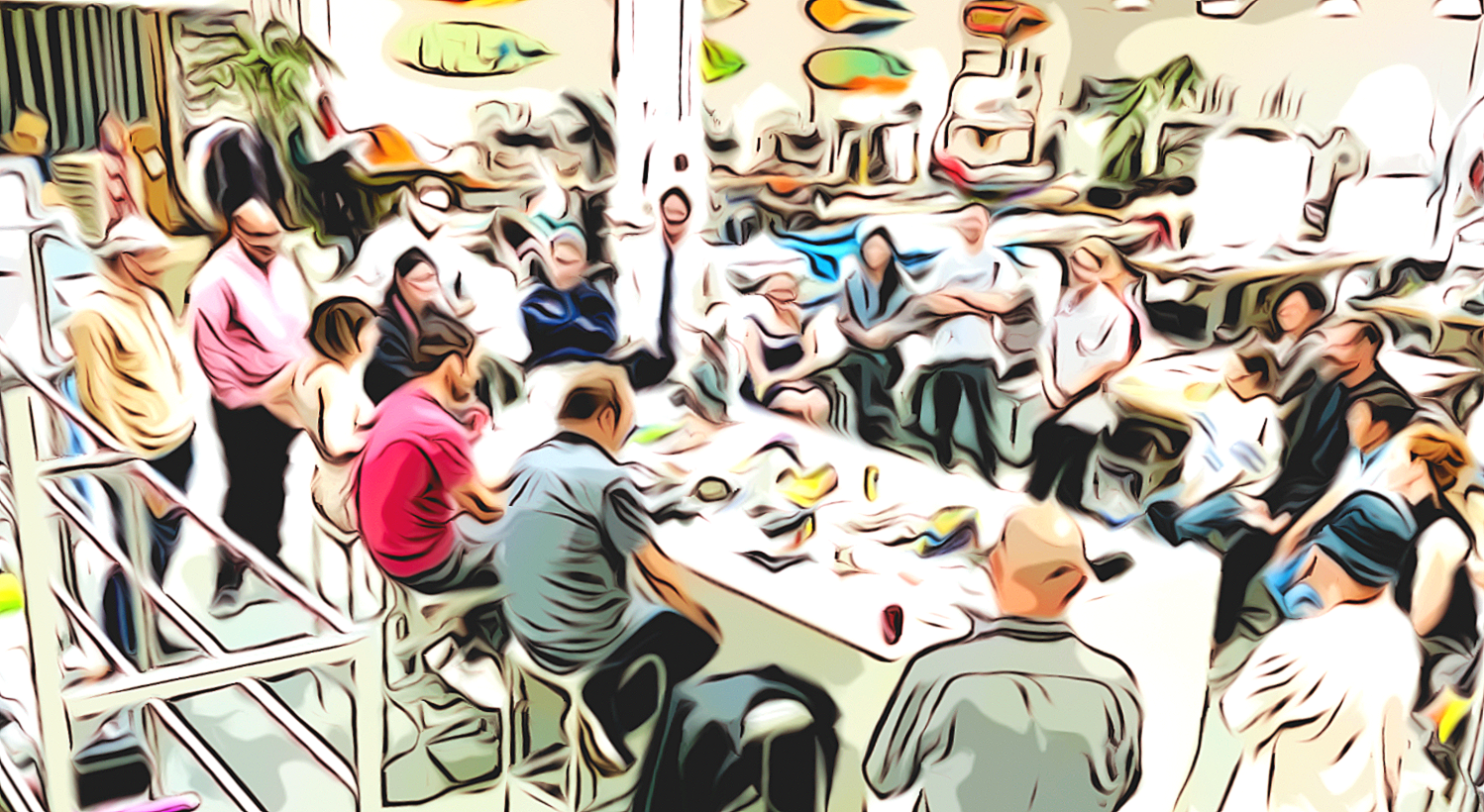 People gathered around a table in a crowded room, participating in a meeting or workshop.