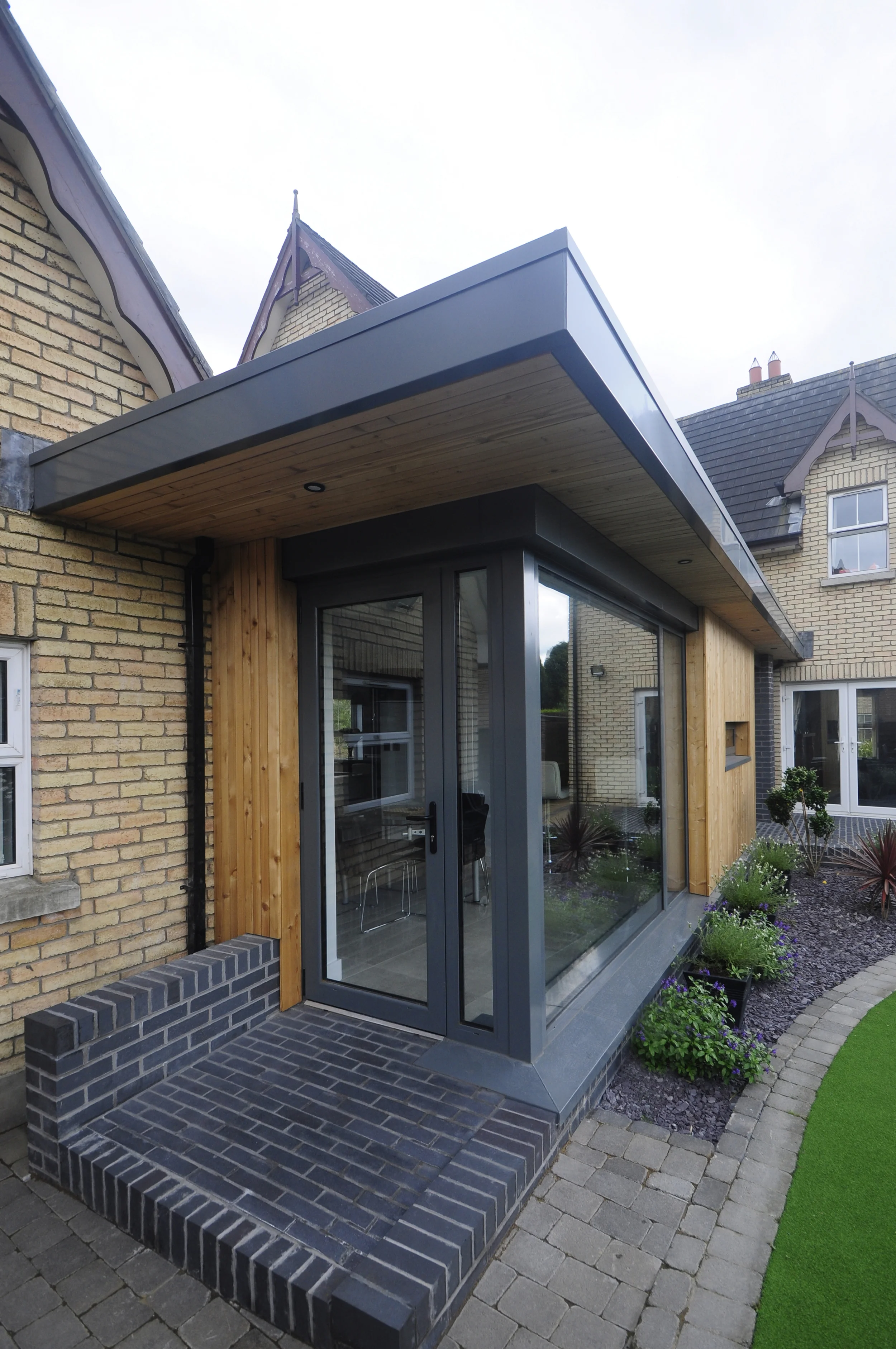 Residential Extension, Jordanstown This project seen the complete renovation of the dwellings existing kitchen, the infill of an existing car port and a new rear extension. The renovations were tailored to the residents way of living, centralised around the new kitchen and bar area. The plan was organised off the axis of the new extension to the rear, with a new kitchen and bar area along one side. The existing car port has been in filled complete with a cut roof, increasing the sense of space within the new sunken seating area. The glazed extension to the rear allows views out to an existing garden, and provides much needed space for dining.