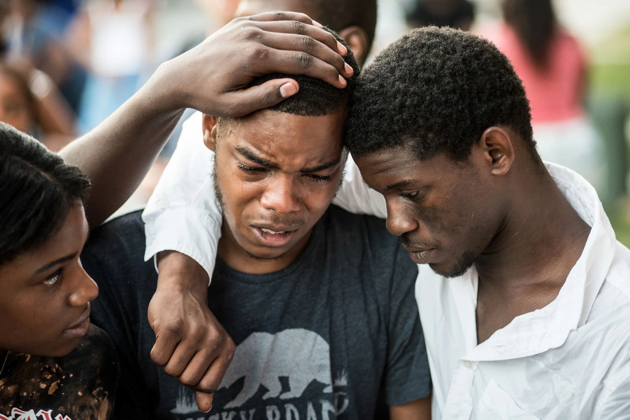 Zhauil Williams, 18, (center) is comforted by Will Miles, 22, (right) during a Tuesday night vigil for 16-year old Asir Brown, their friend who was gunned down by a drive-by shooting a few minutes before midnight on Saturday outside of a Grays Ferry home in Philadelphia. He was pronounced dead on Sunday, July 3, 2016. (Michael Ares / Philadelphia Inquirer)