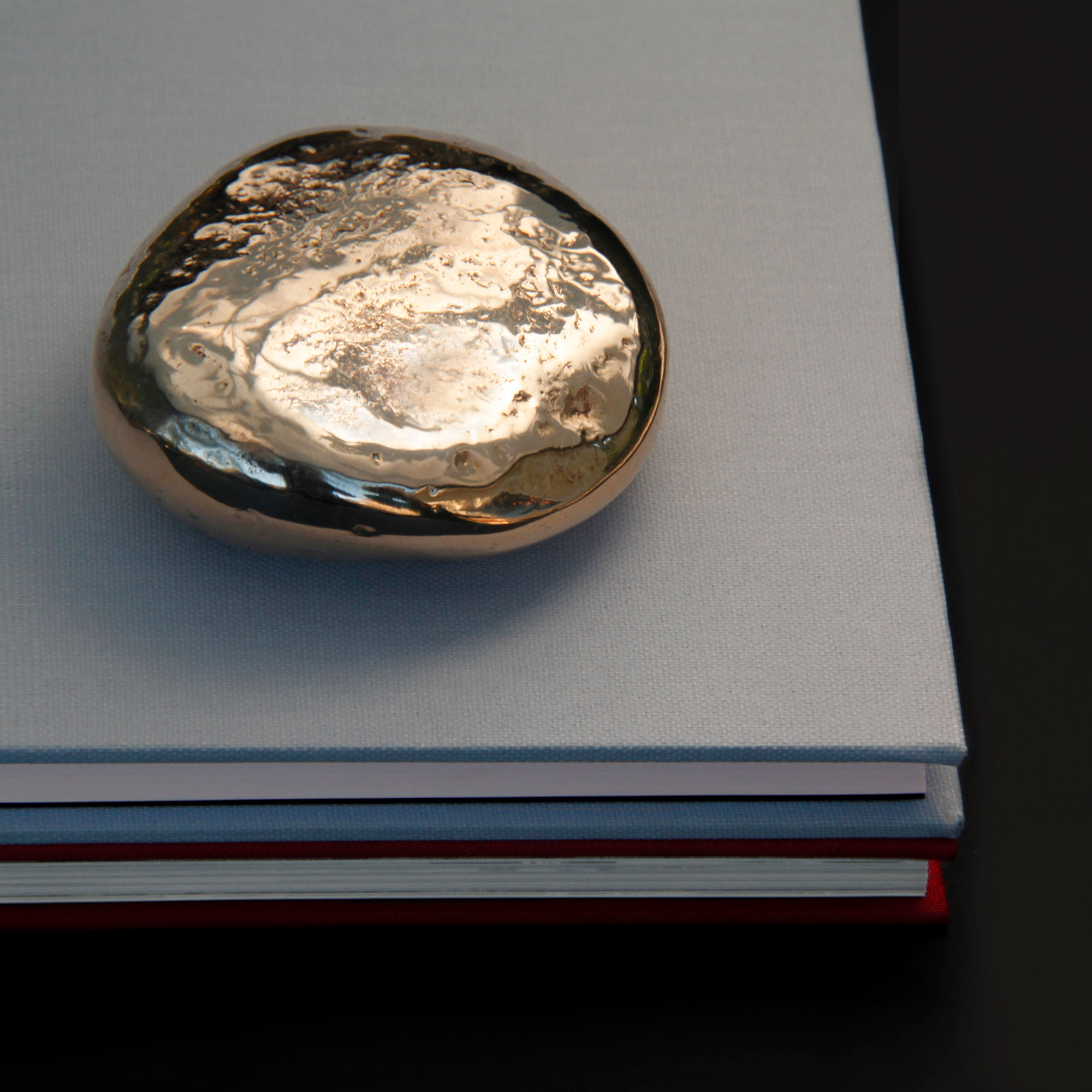 Pebble paperweight sitting on a pile of books