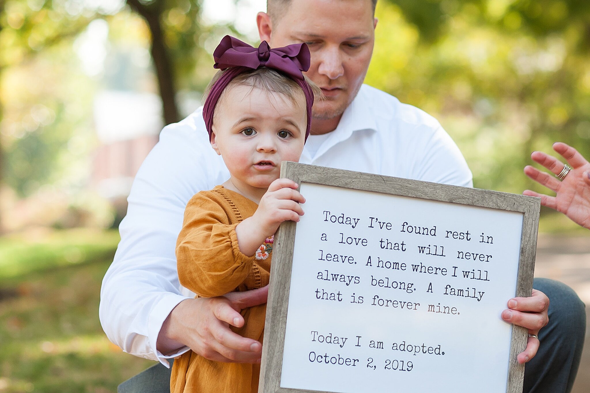 Wendy Zook discusses using props in family photos while little girl holds sign with adoption quote