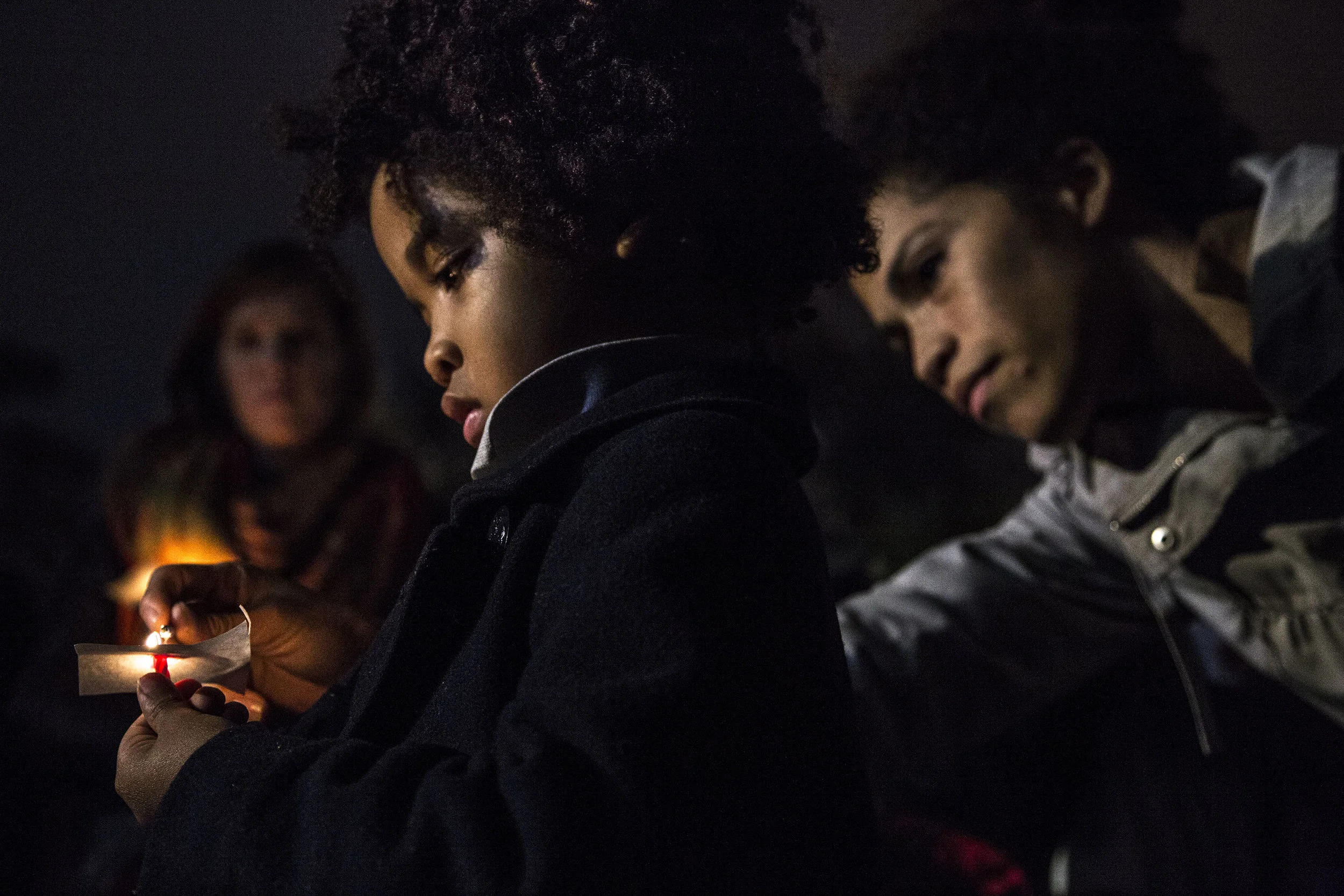 A mother lights the candle of her son during a candlelight vigil outside the White House, the evening after the 2016 presidential election.