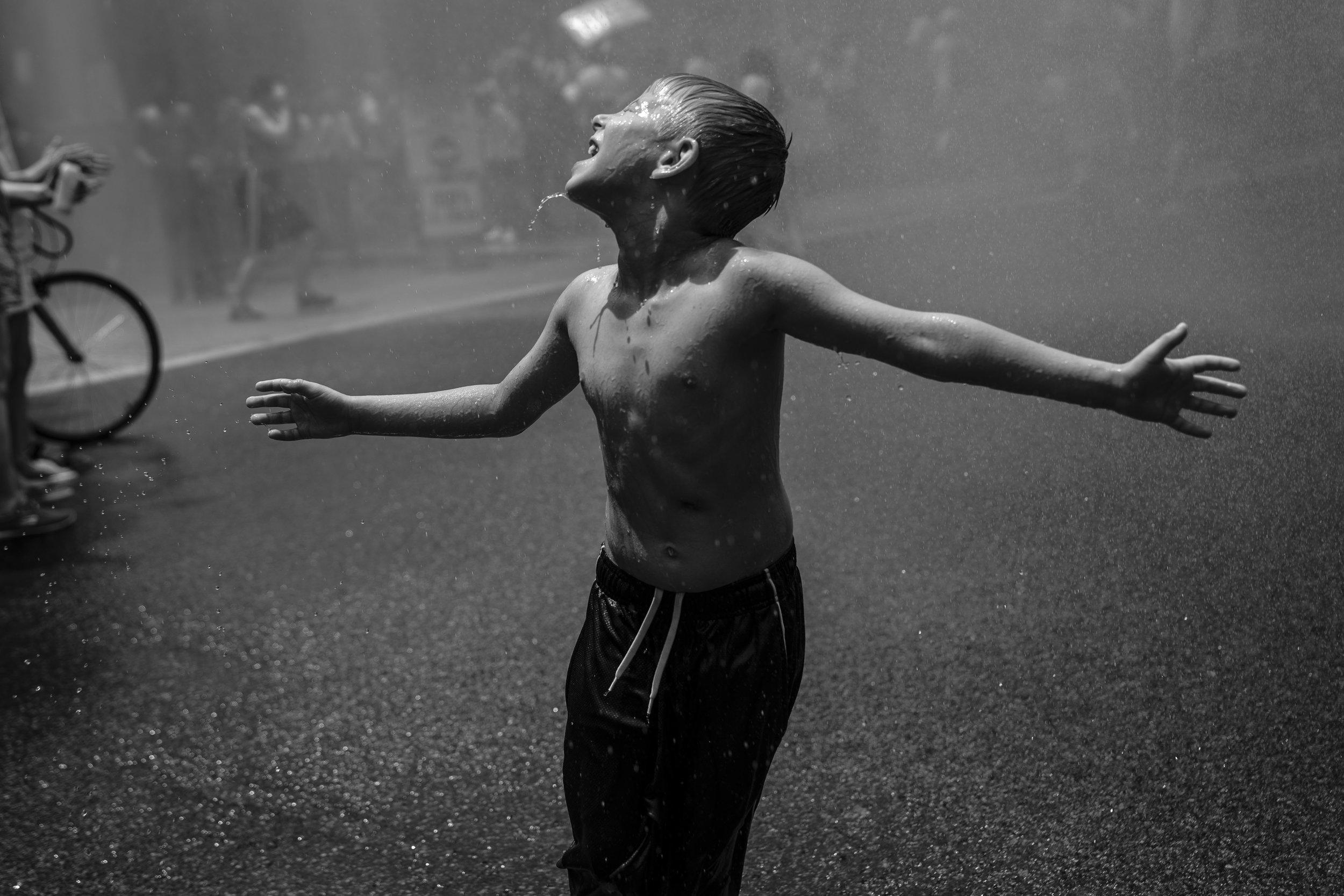   A boy cools off in water sprayed from a fire truck during a protest against the Trump administration's policy on separating immigrant families.  