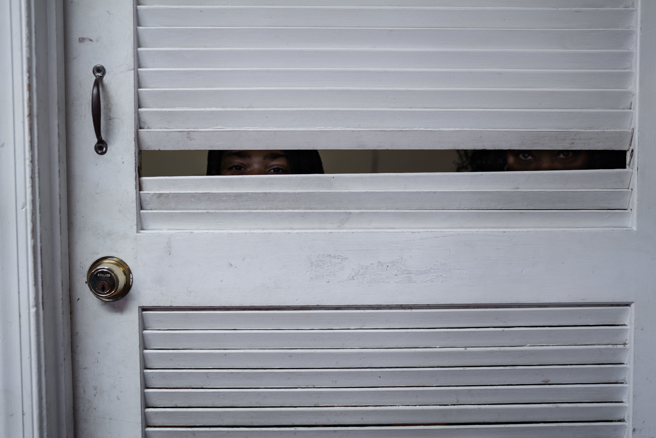   A young girl and a woman look through a door at a barber shop in Fredericksburg, VA.   